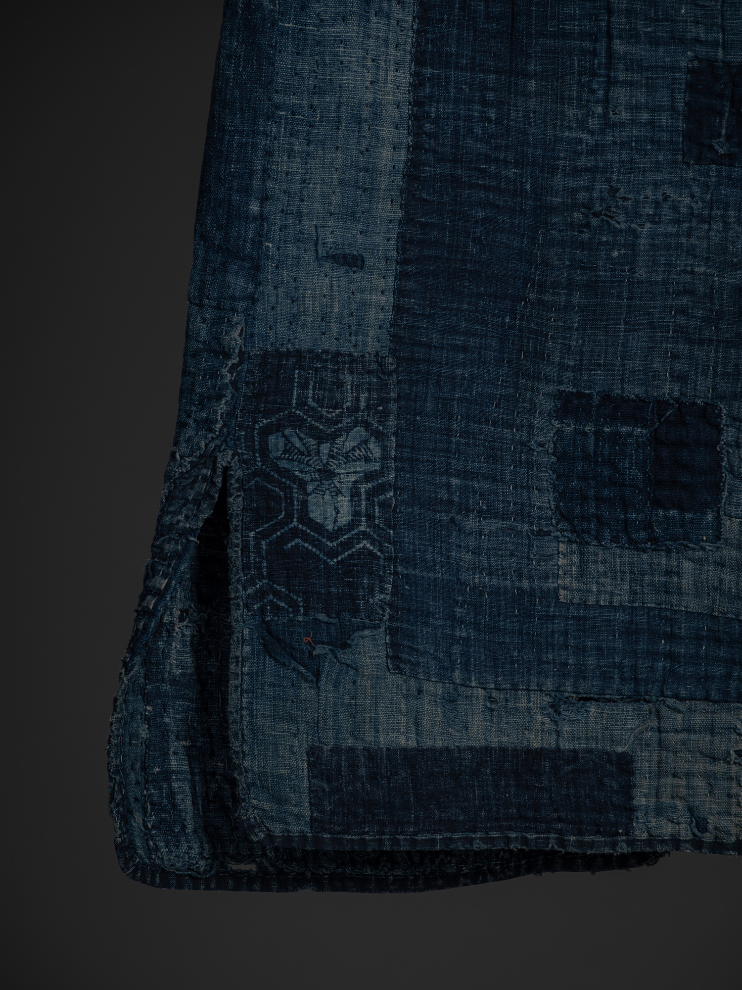 Close-up of the lower left back of the boro work coat, showing the opposite side vent framed by...