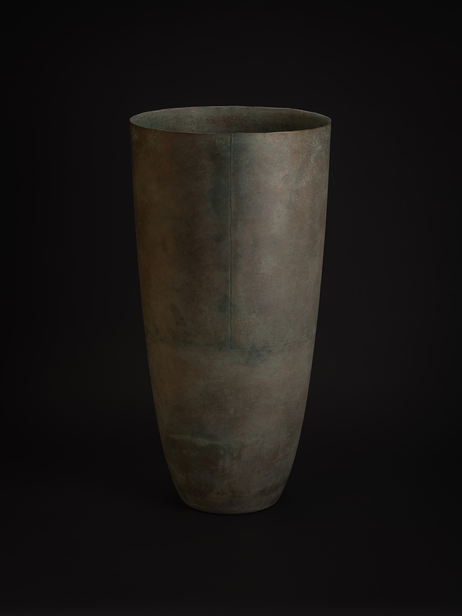 Existing in Bronze by Hatakeyama is a large bronze vessel with a tall, tapering form that widens...