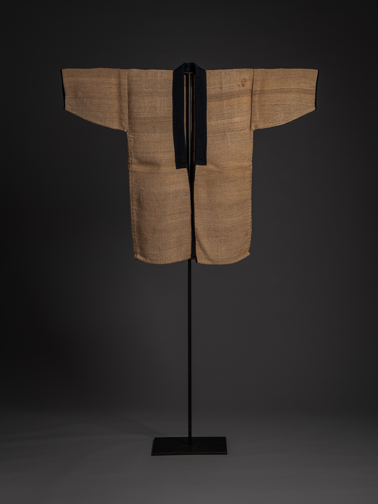 Full front view of a Japanese fujifu work coat displayed on a stand. Woven from natural brown wisteria...