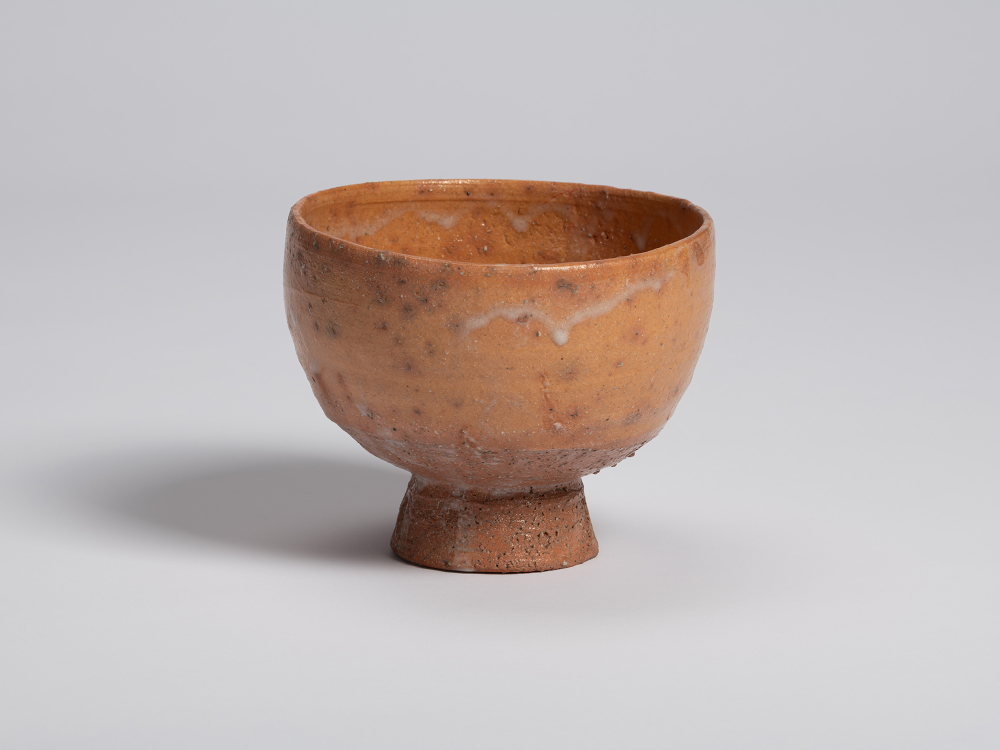 Front view of Goki Chawan. A band of pale glaze drips across the upper portion of the bowl, contrasting...