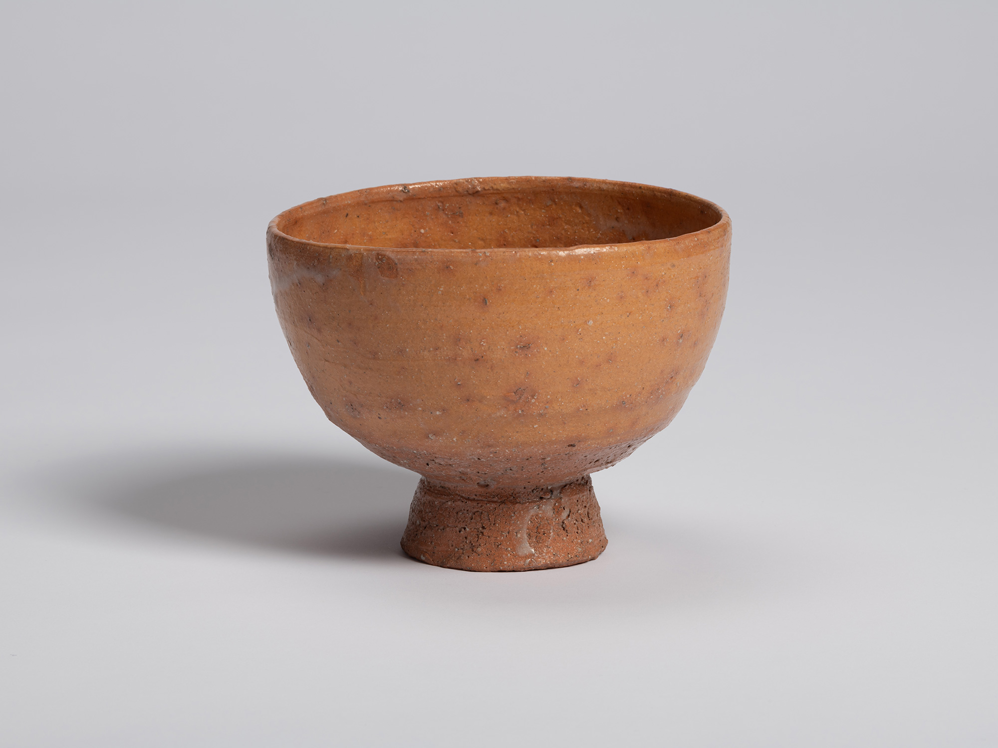View of Goki Chawan showing a smoother section of the bowl's surface. The orange-brown glaze is...
