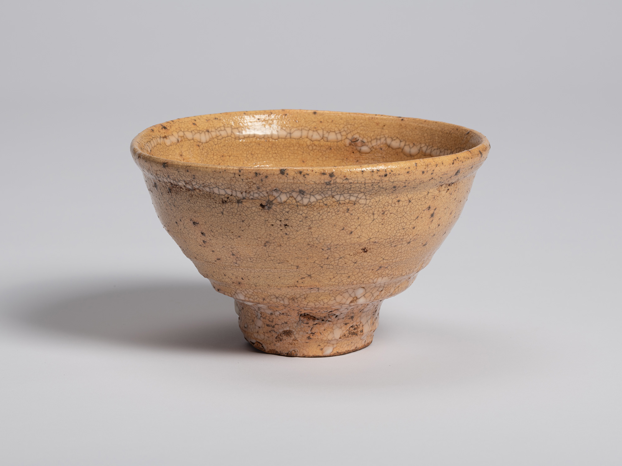 View of Ido-Style Tea Bowl showing a lighter section of the bowl's exterior. Fine crackling extends...