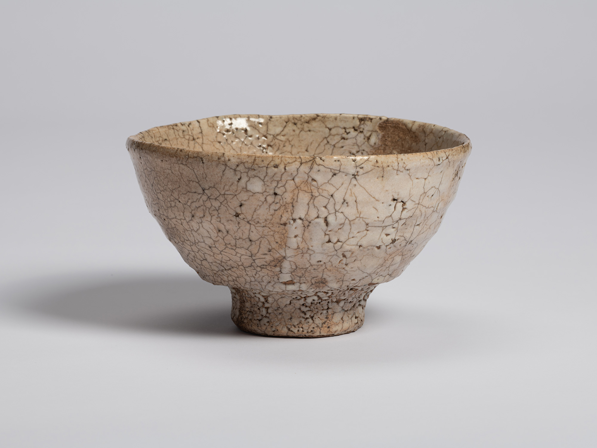 View of Ido Chawan by Shiro Tsujimura. The tea bowl has a broad, gently flaring form covered in...