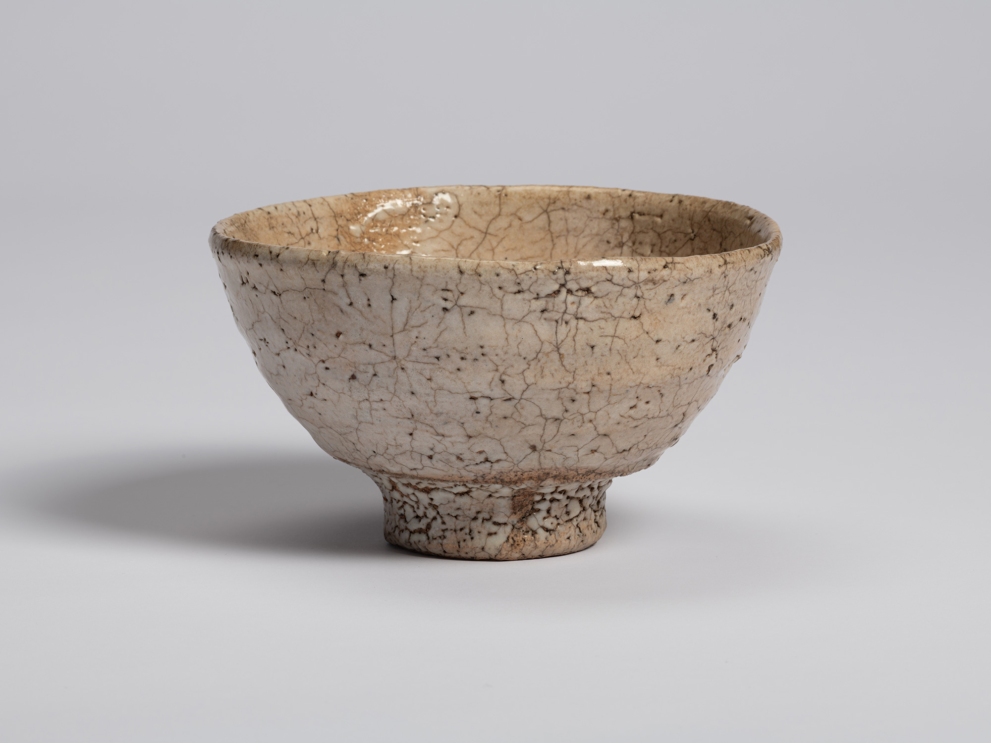 Front view of Ido Chawan. The bowl's rounded body tapers toward a compact foot ring, and the crackled...