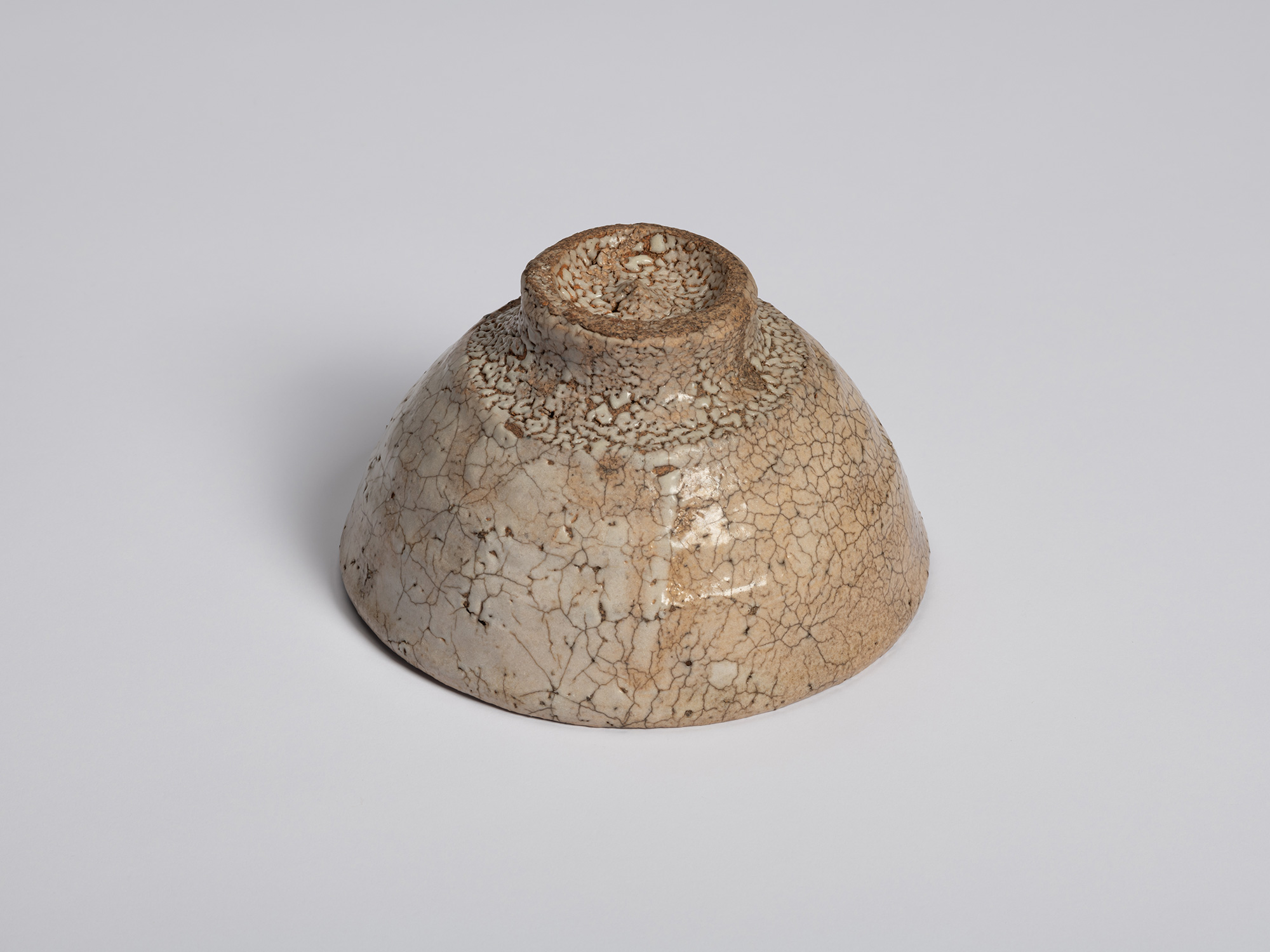 Underside view of Ido Chawan showing the bowl's foot ring and base. The foot is heavily textured...