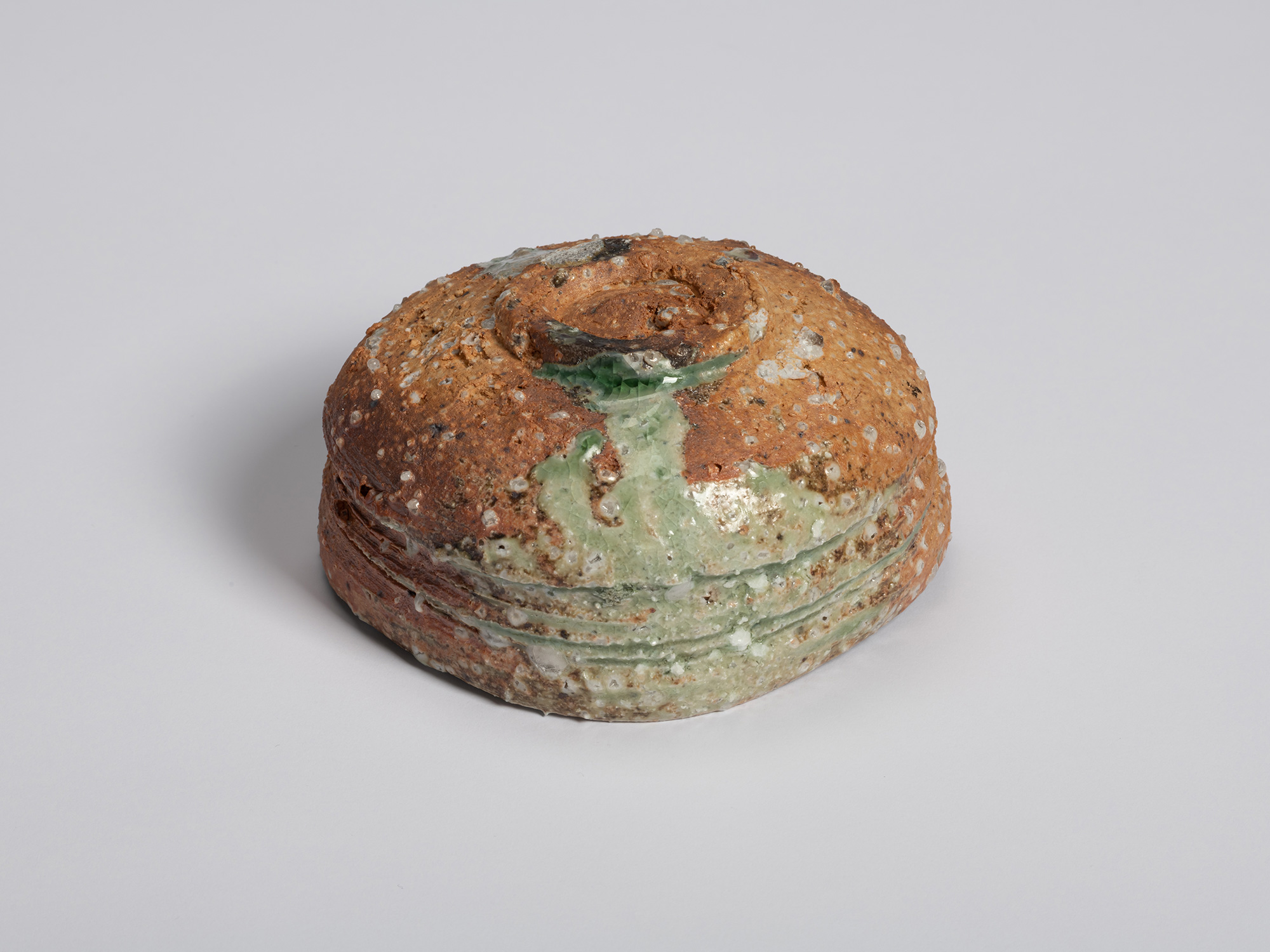 Three-quarter view of the underside of an Iga tea bowl by Shiro Tsujimura. The bowl's rounded base...