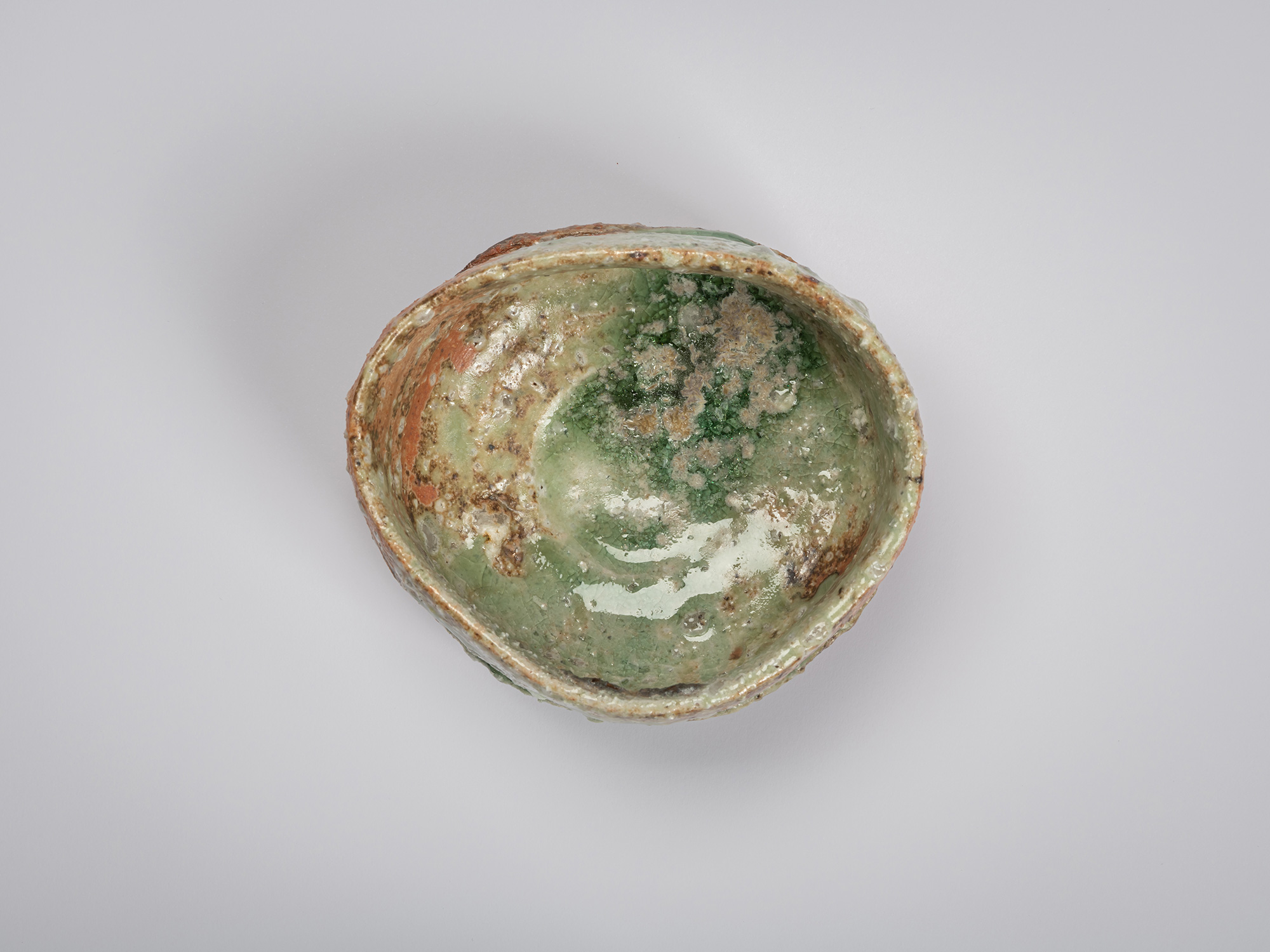 Overhead view of an Iga tea bowl by Shiro Tsujimura. The interior is coated in a glossy pale green...