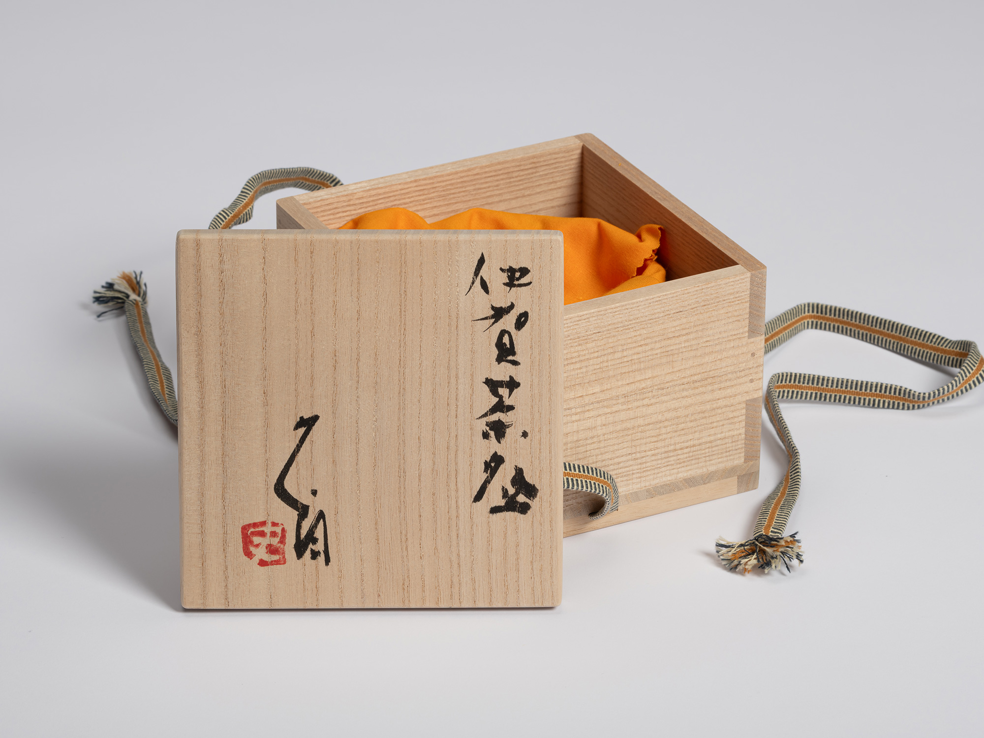 Wooden tomobako for an Iga tea bowl by Shiro Tsujimura shown with the lid leaning against the open...