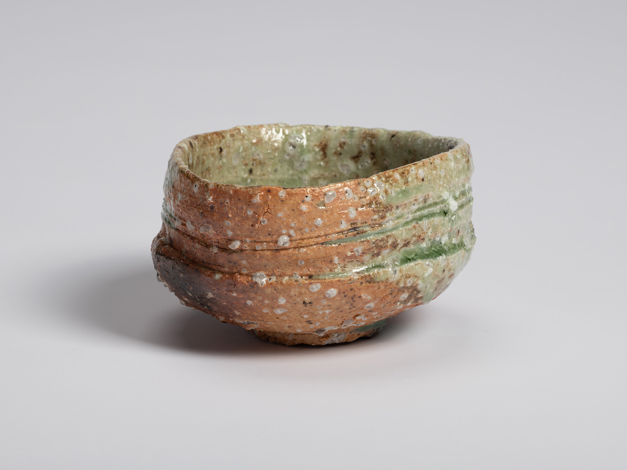 Iga tea bowl by Shiro Tsujimura. Horizontal throwing marks and bands of green ash glaze wrap around...