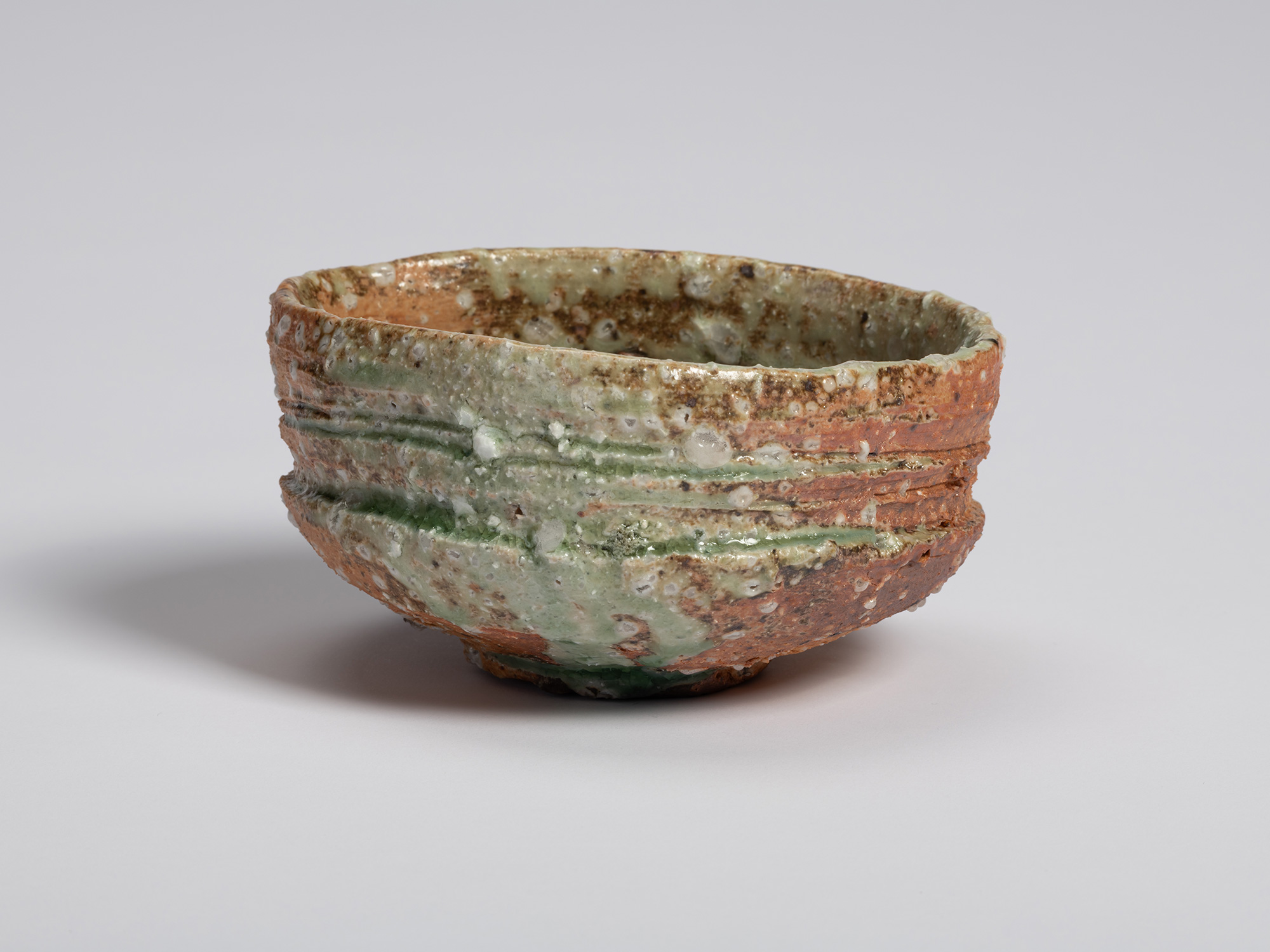 View of an Iga tea bowl by Shiro Tsujimura. The hand-formed bowl features an irregular oval rim...