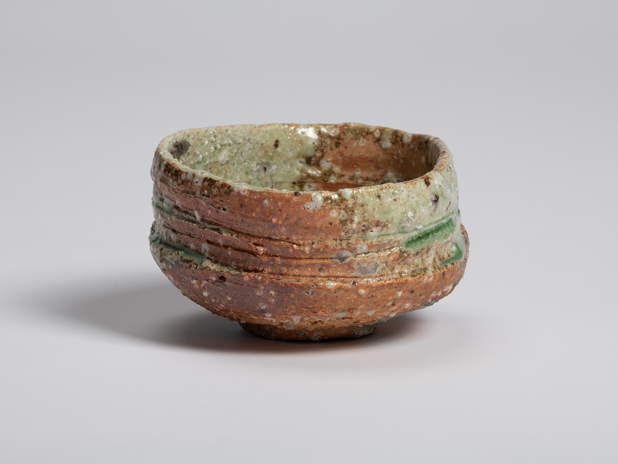 Side view of Iga tea bowl by Shiro Tsujimura showing its asymmetrical profile and deeply textured...