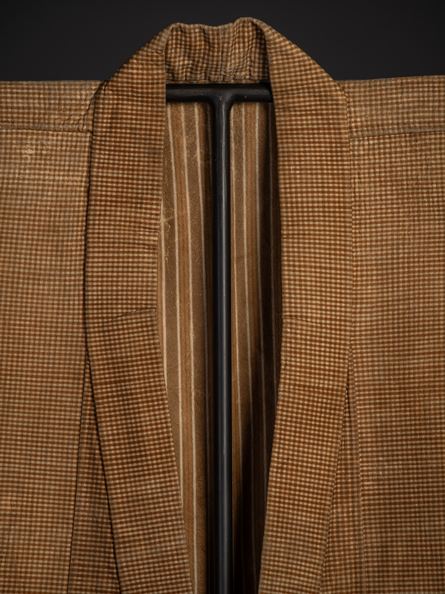 Close-up of the folded collar showing the finely checked exterior fabric framing the brown-and-cream...