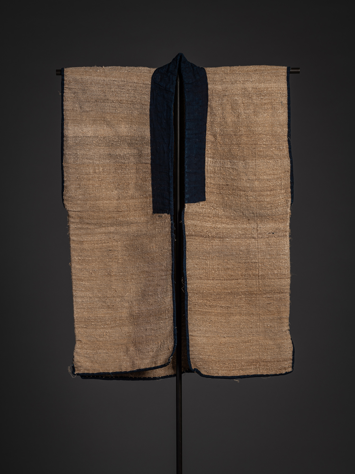 Front view of an okusozakkuri sodenashi sleeveless work garment displayed on a stand. The garment...