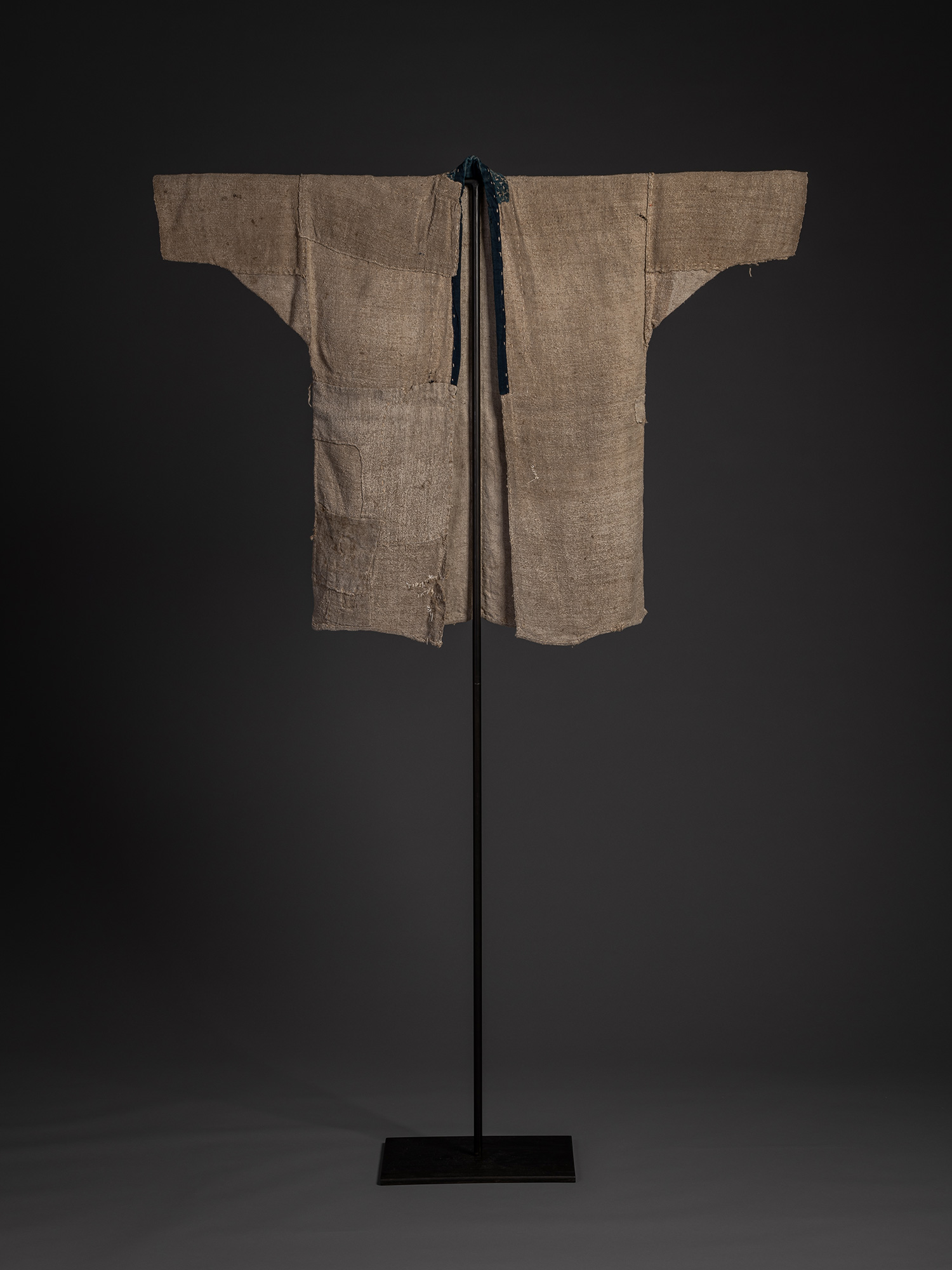 Full front view of the okusozakkuri displayed on a stand with the open front and narrow indigo-dyed...