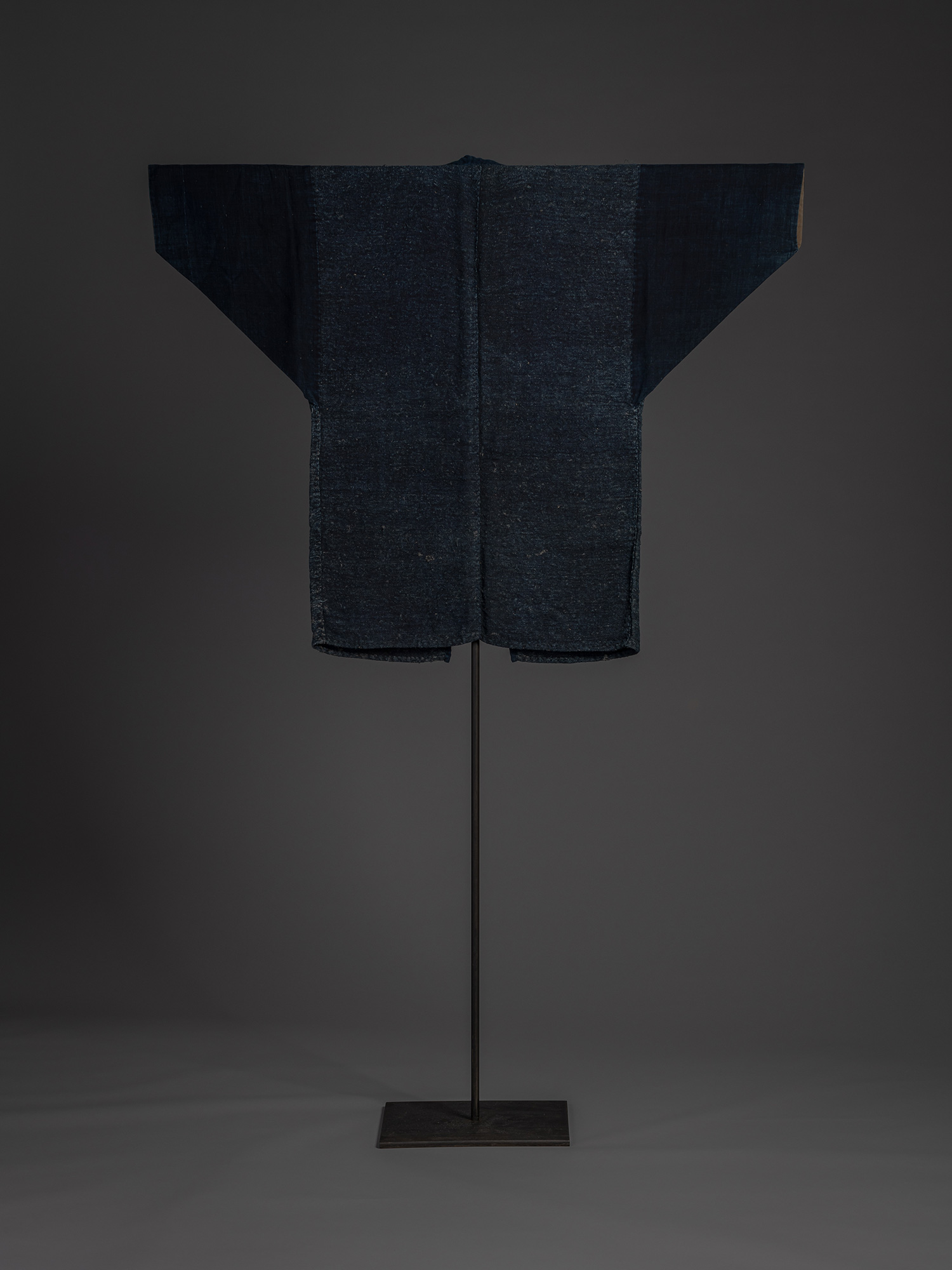 Back view of an okusozakkuri work jacket woven from coarse indigo-dyed cloth. The body is made...