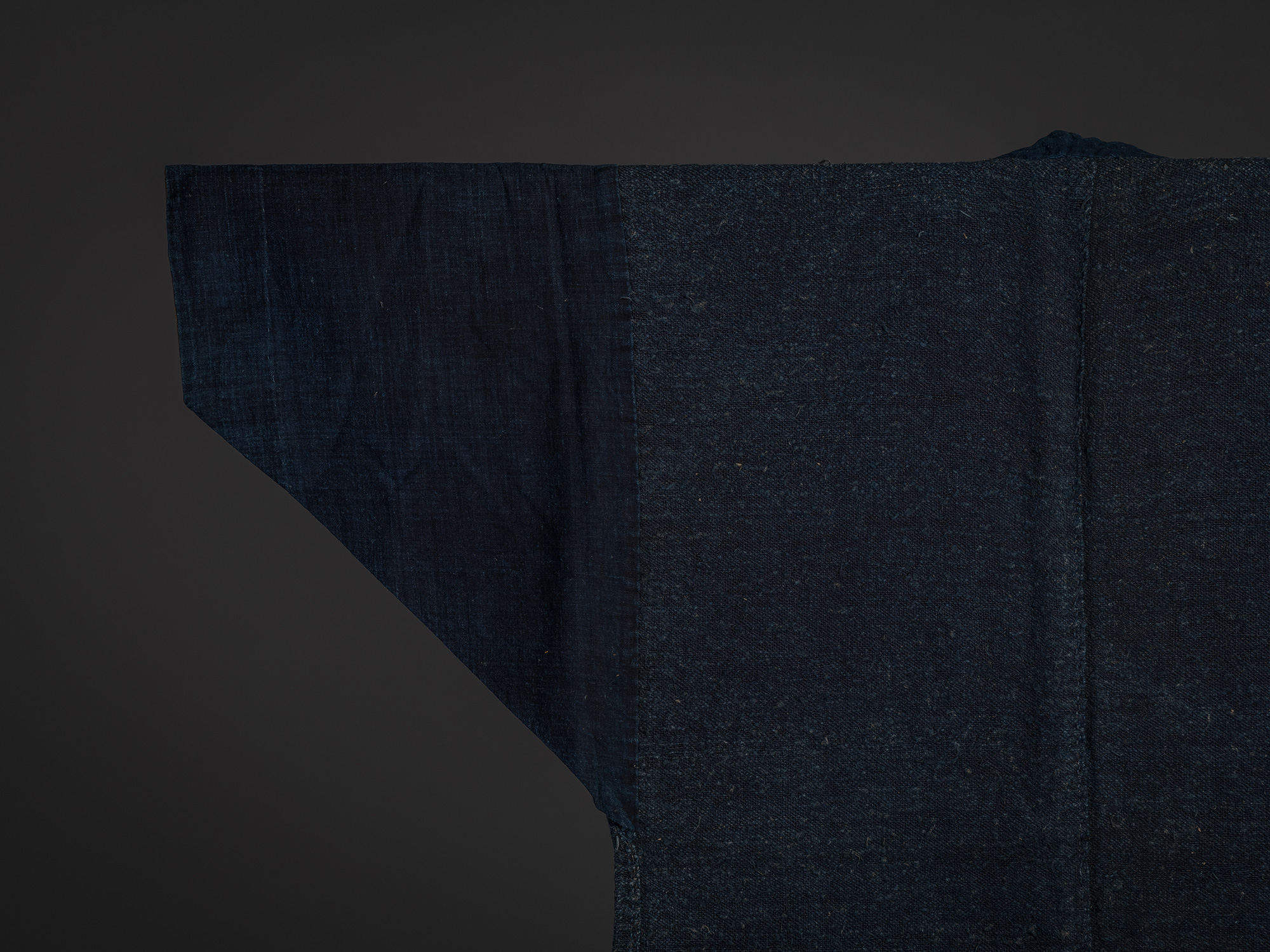 Close-up of the back left shoulder of the okusozakkuri work jacket. The image highlights the transition...