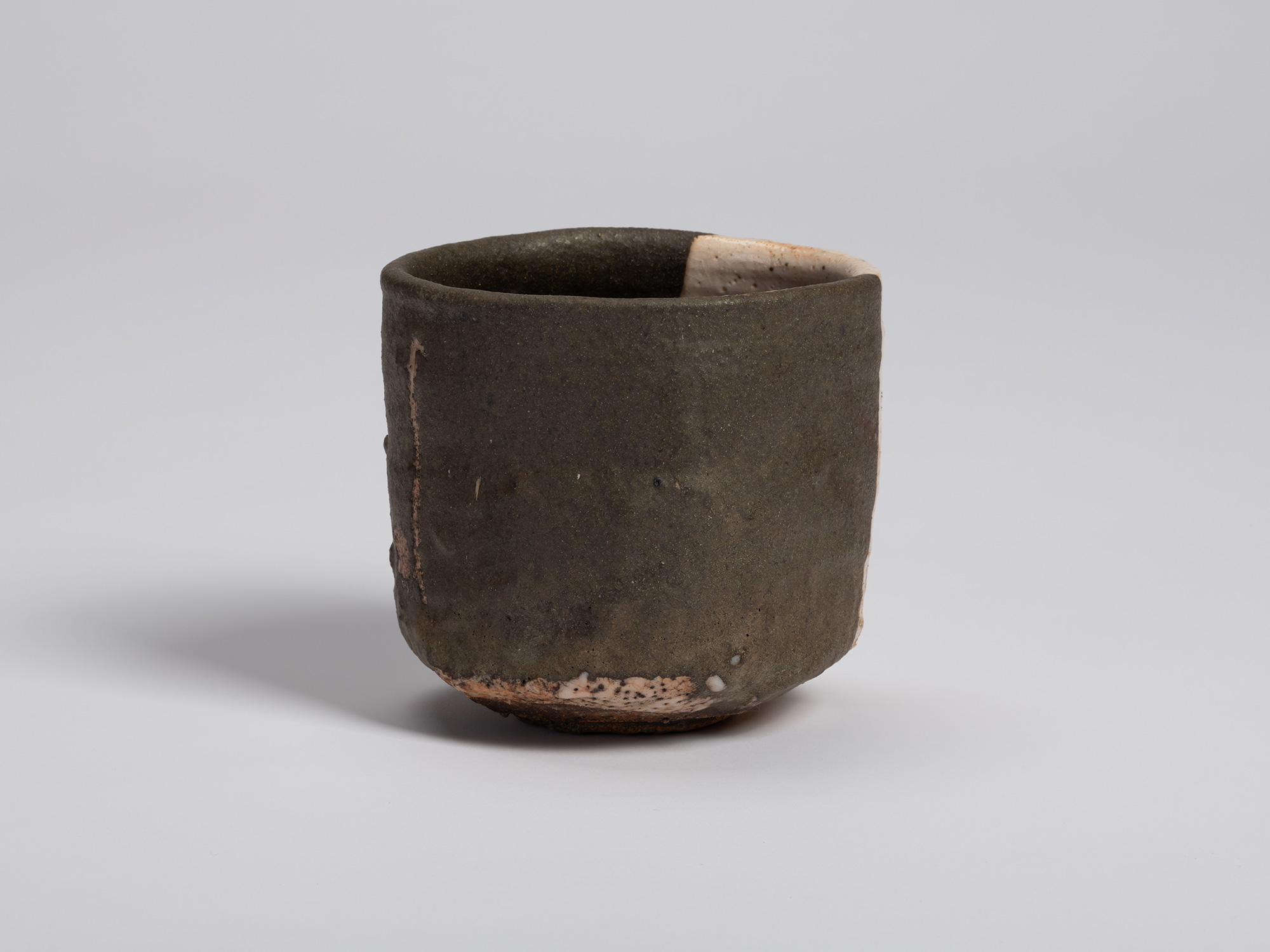 Rear view of the tea bowl showing a broad field of dark glaze with subtle tonal variations. Incised...