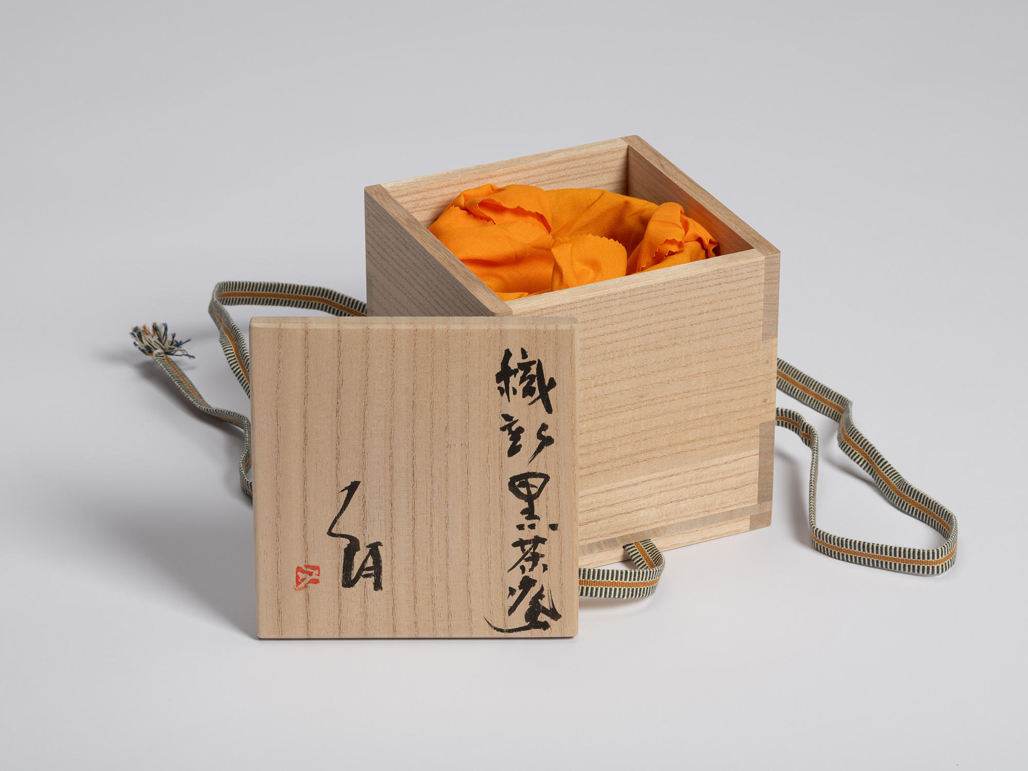 Open paulownia wood tomobako with the lid placed in front of the box. The interior contains an...