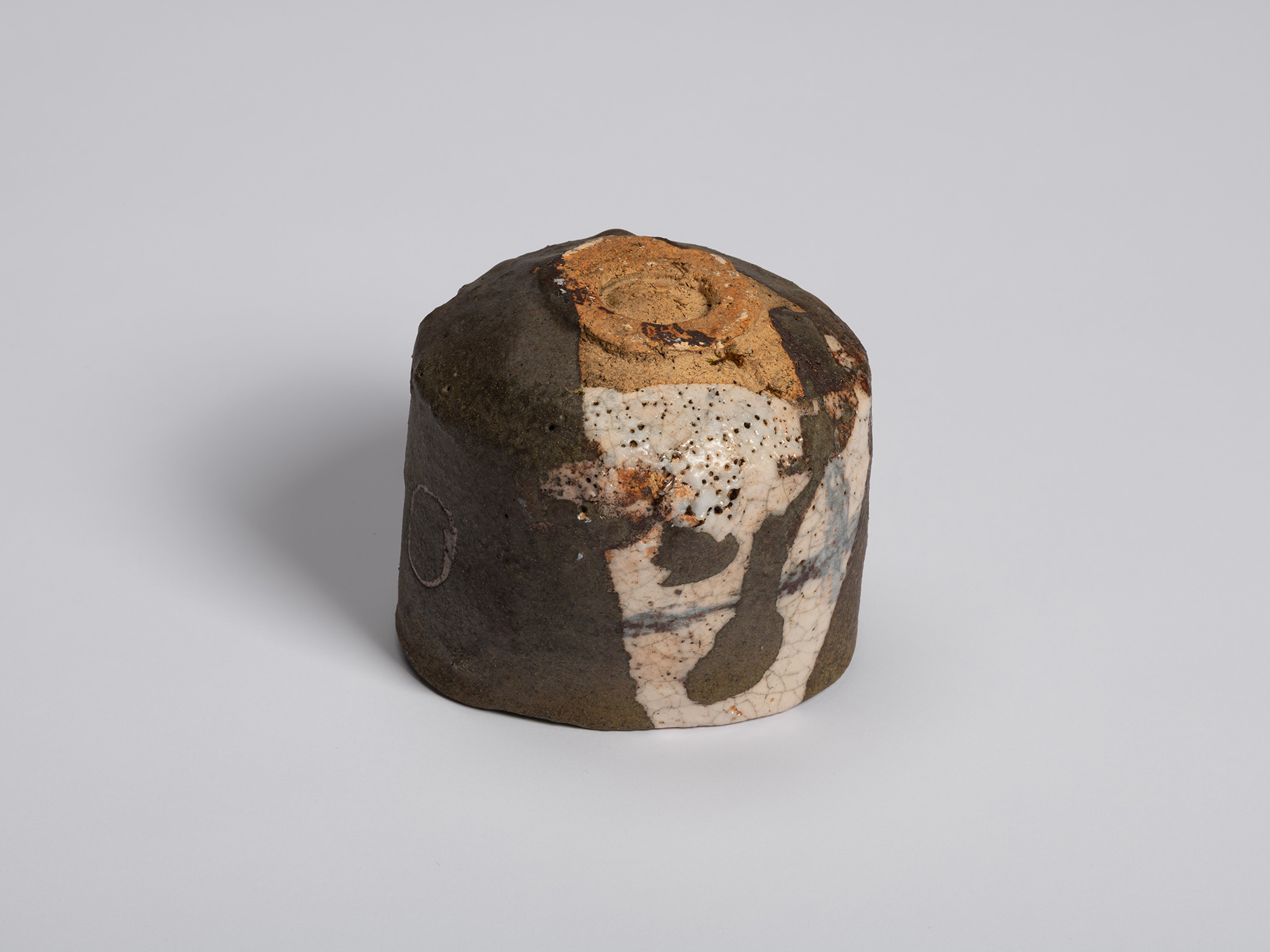 Underside view of the Chawan resting upside down. The dark exterior wraps around the body, while...