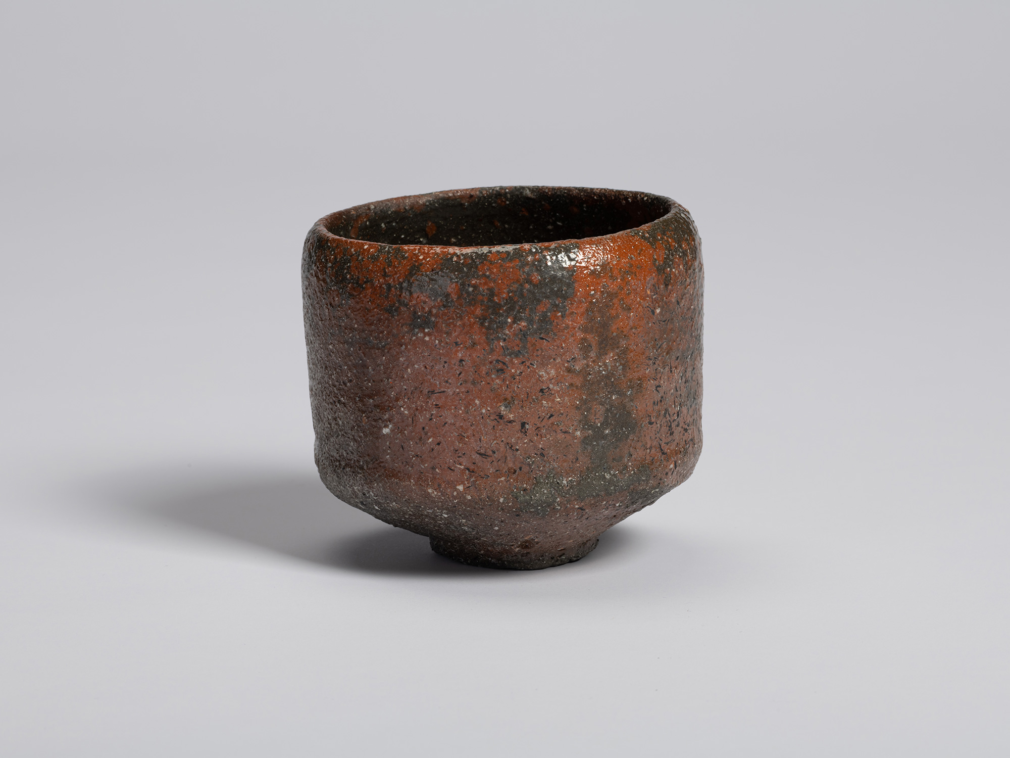 View of a raku-style tea bowl by Shiro Tsujimura. The cylindrical, hand-formed vessel has gently...