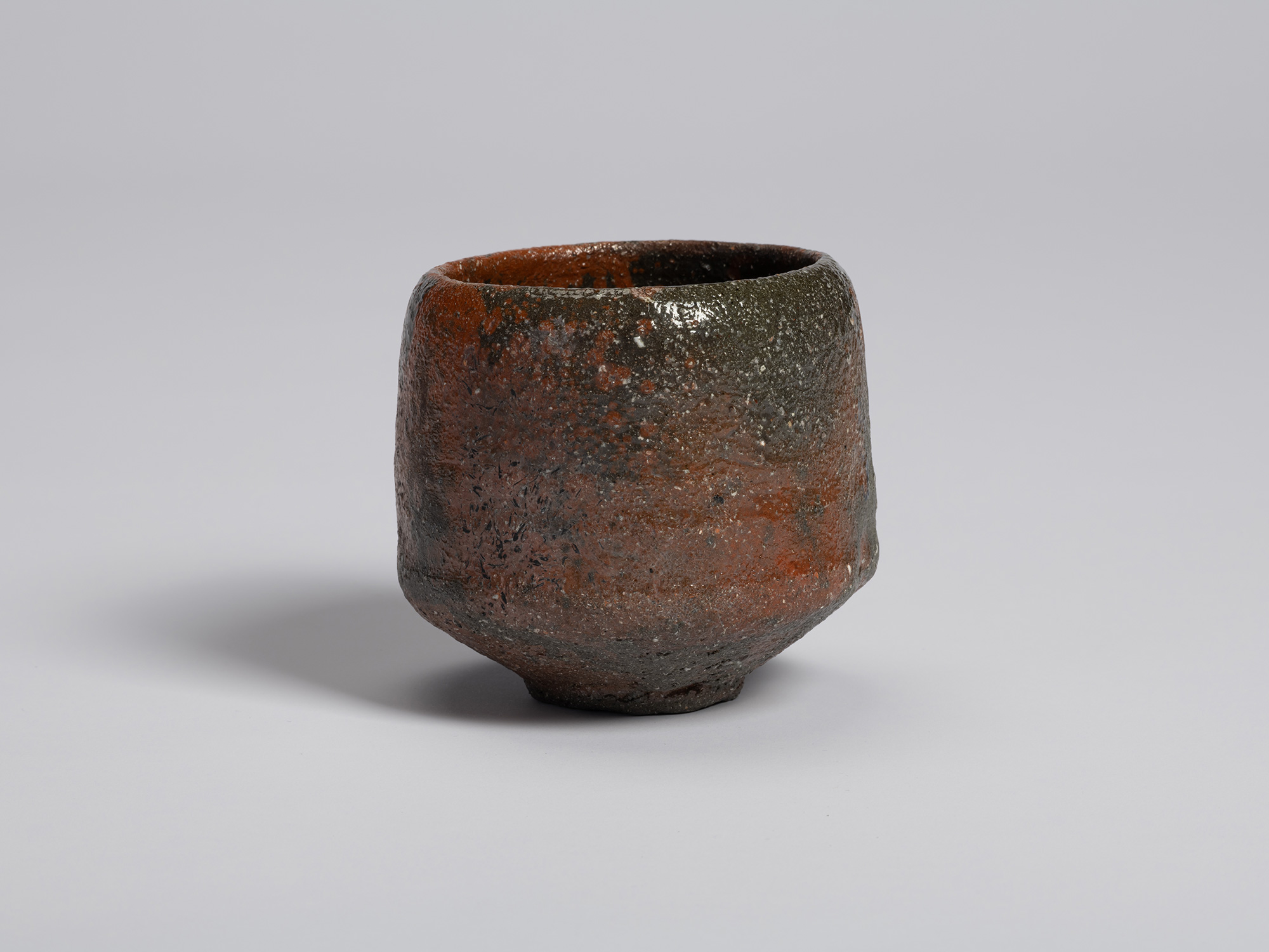 View of Shiro Tsujimura’s raku-style tea bowl. The rounded form rises from a small foot and features...