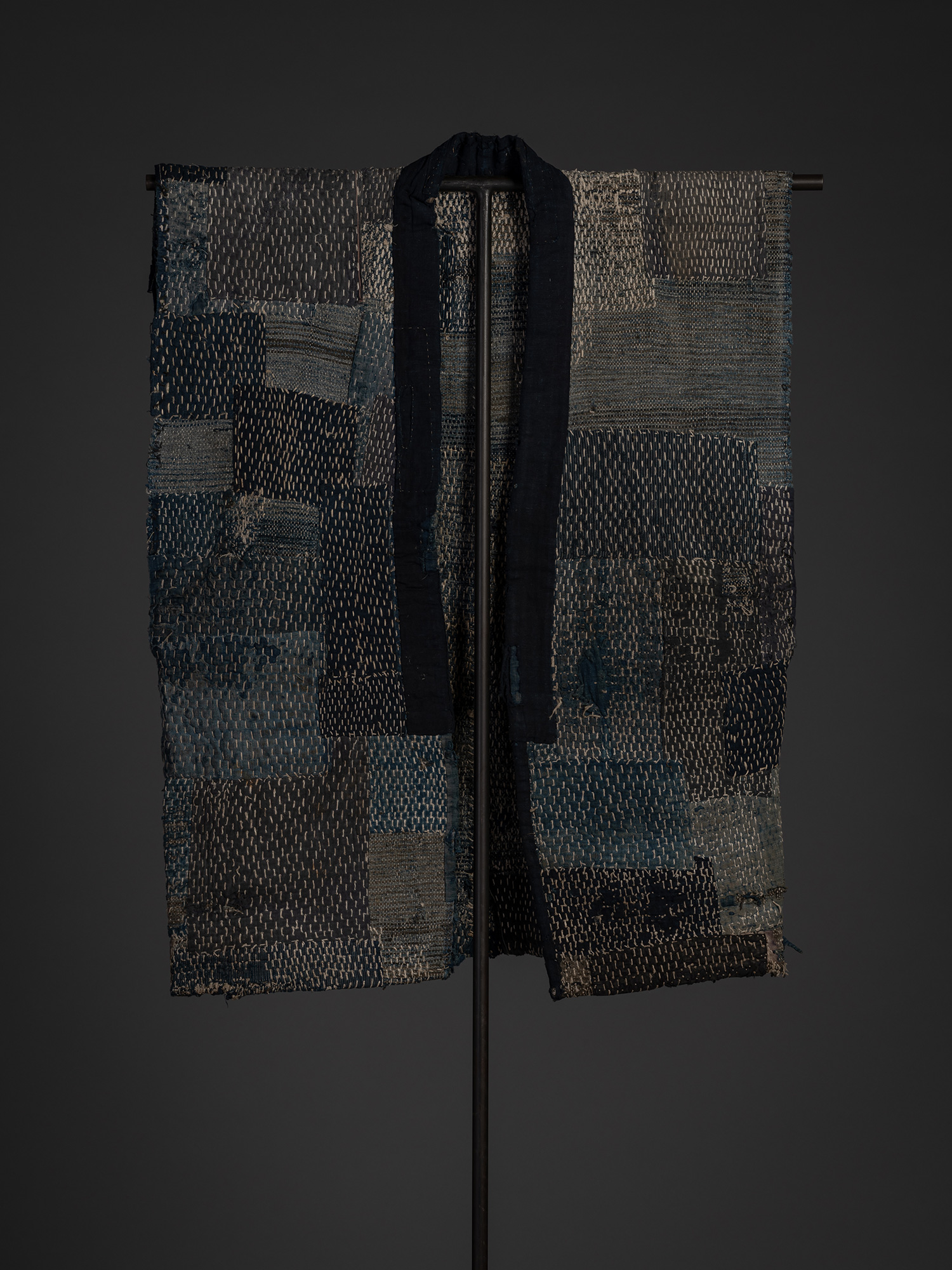 Full front view of the sakiori boro work coat displayed on a stand. The open front is framed by...