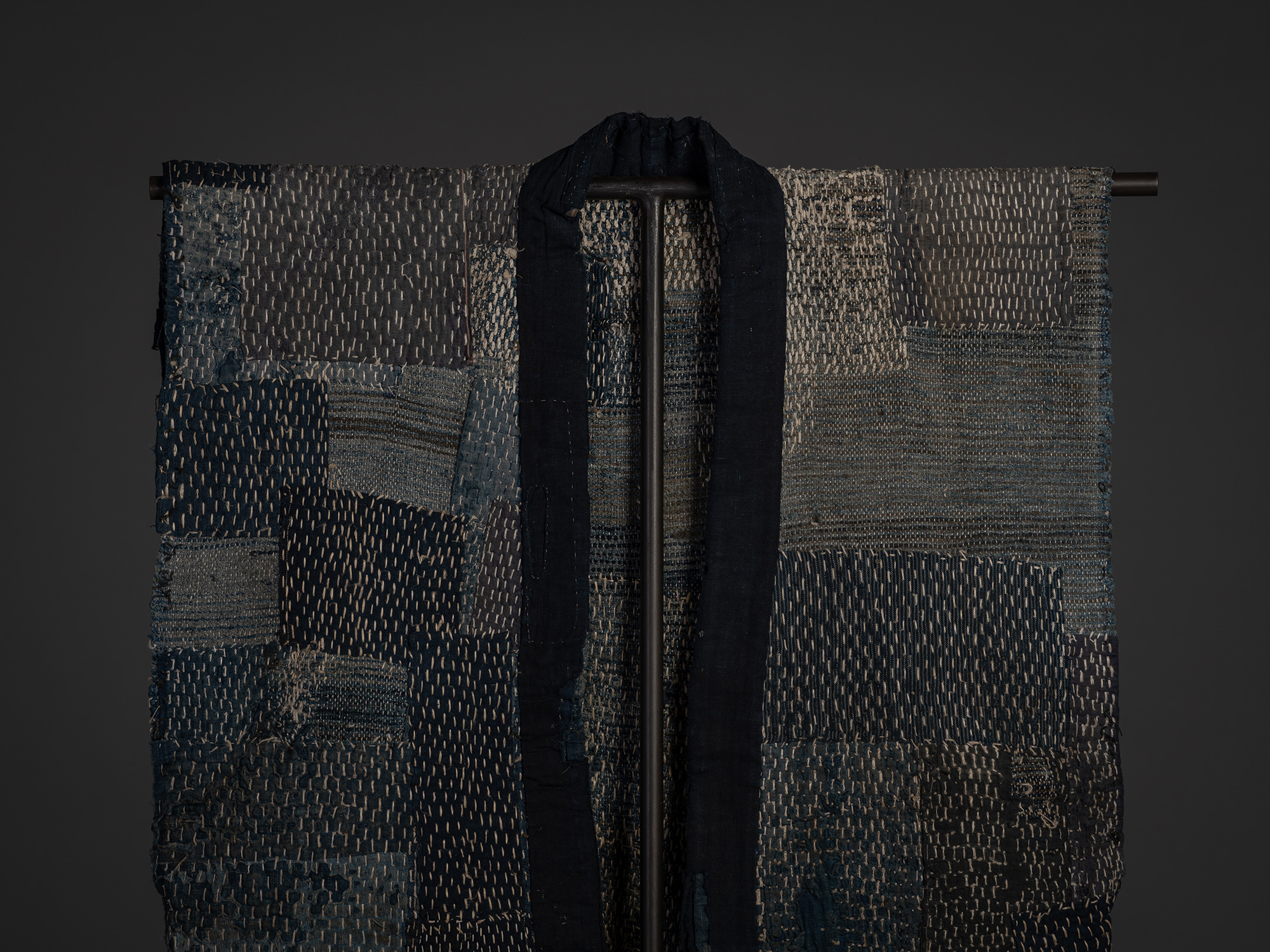 Close-up of the upper front of the sakiori boro work coat, centered on the long dark indigo collar...