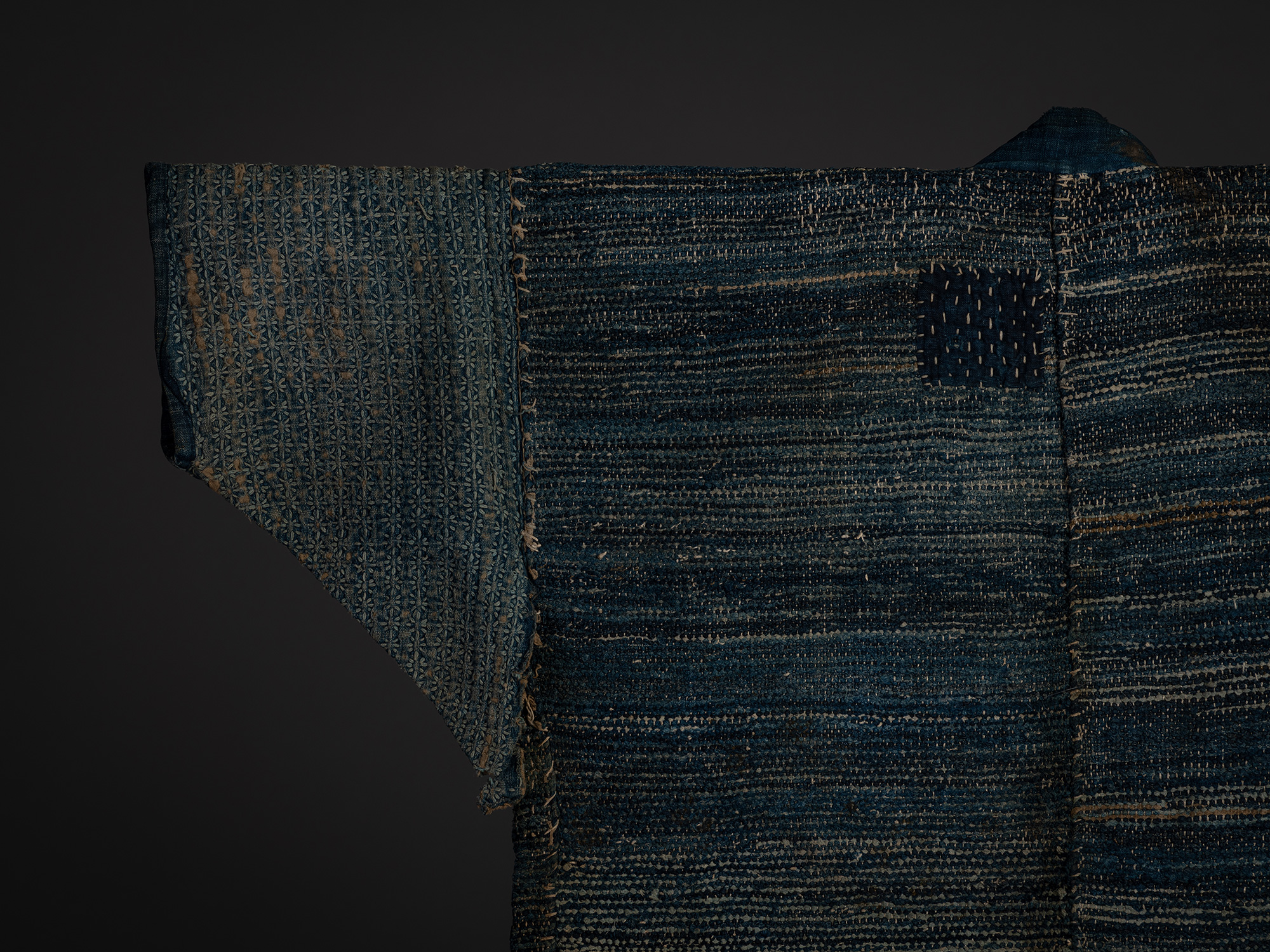 Close-up of the left sleeve and shoulder of the sakiori hanten. The sleeve is woven with a repeating...