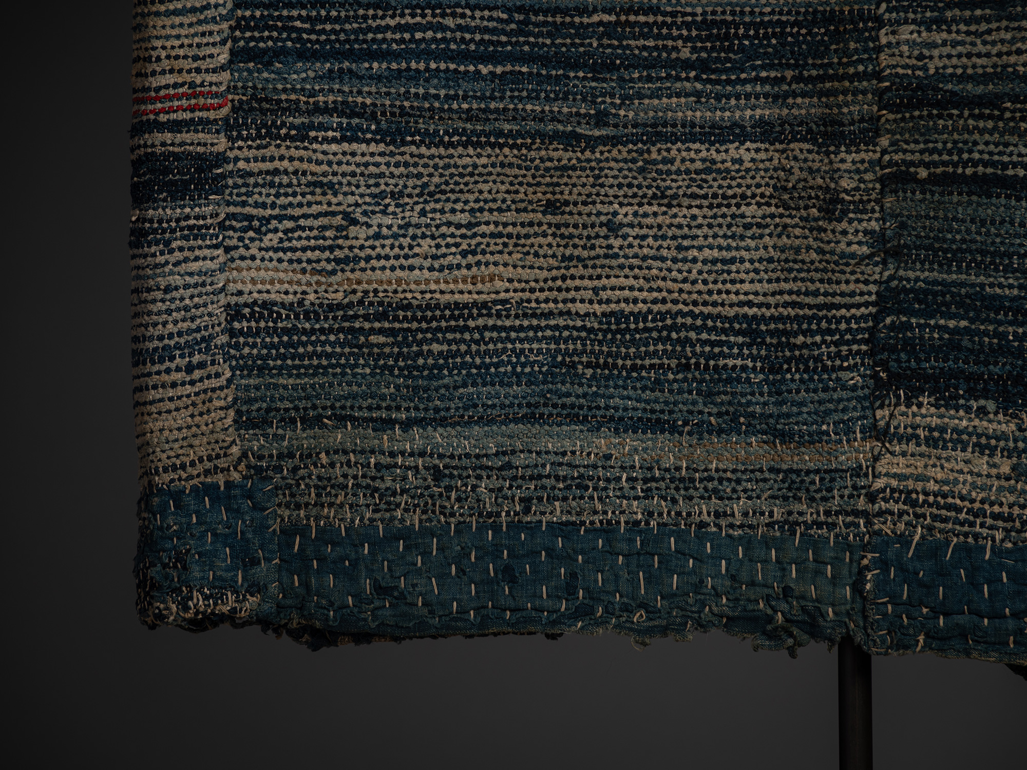 Close-up of the lower back of the indigo-dyed cotton and hemp sakiori hanten. The heavily textured...