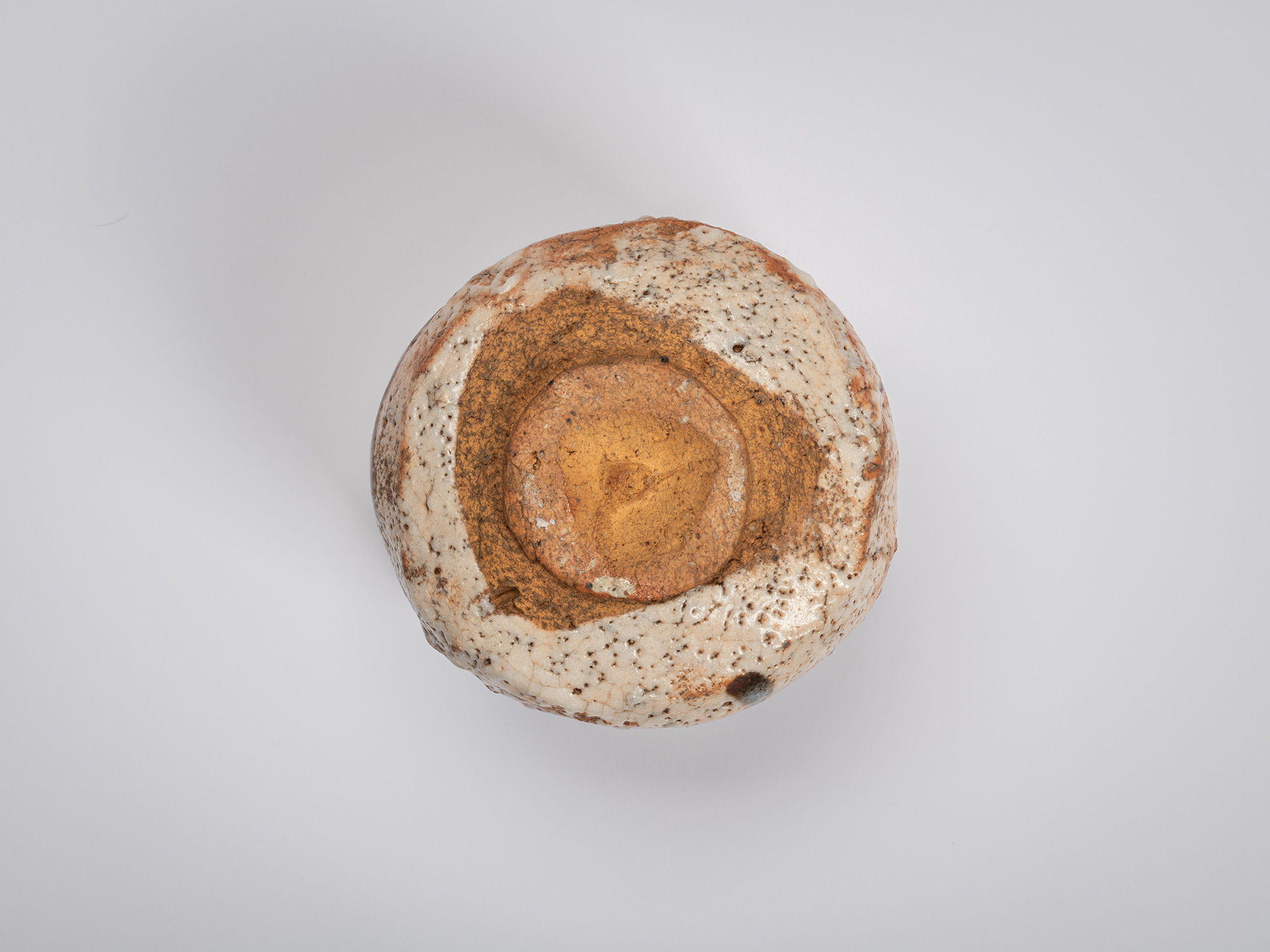 Direct underside view of a Shino Chawan. The circular foot ring surrounds a recessed center of...
