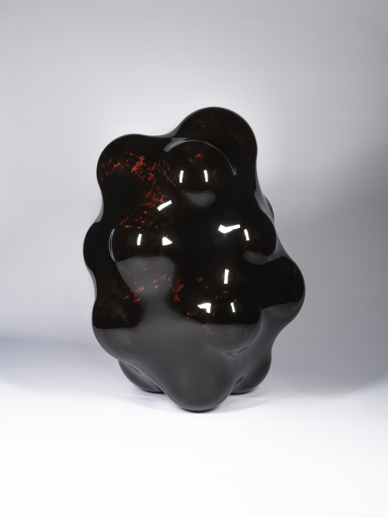 View of Surface Tactility #22 emphasizing its asymmetrical profile and rounded contours. Deep red...