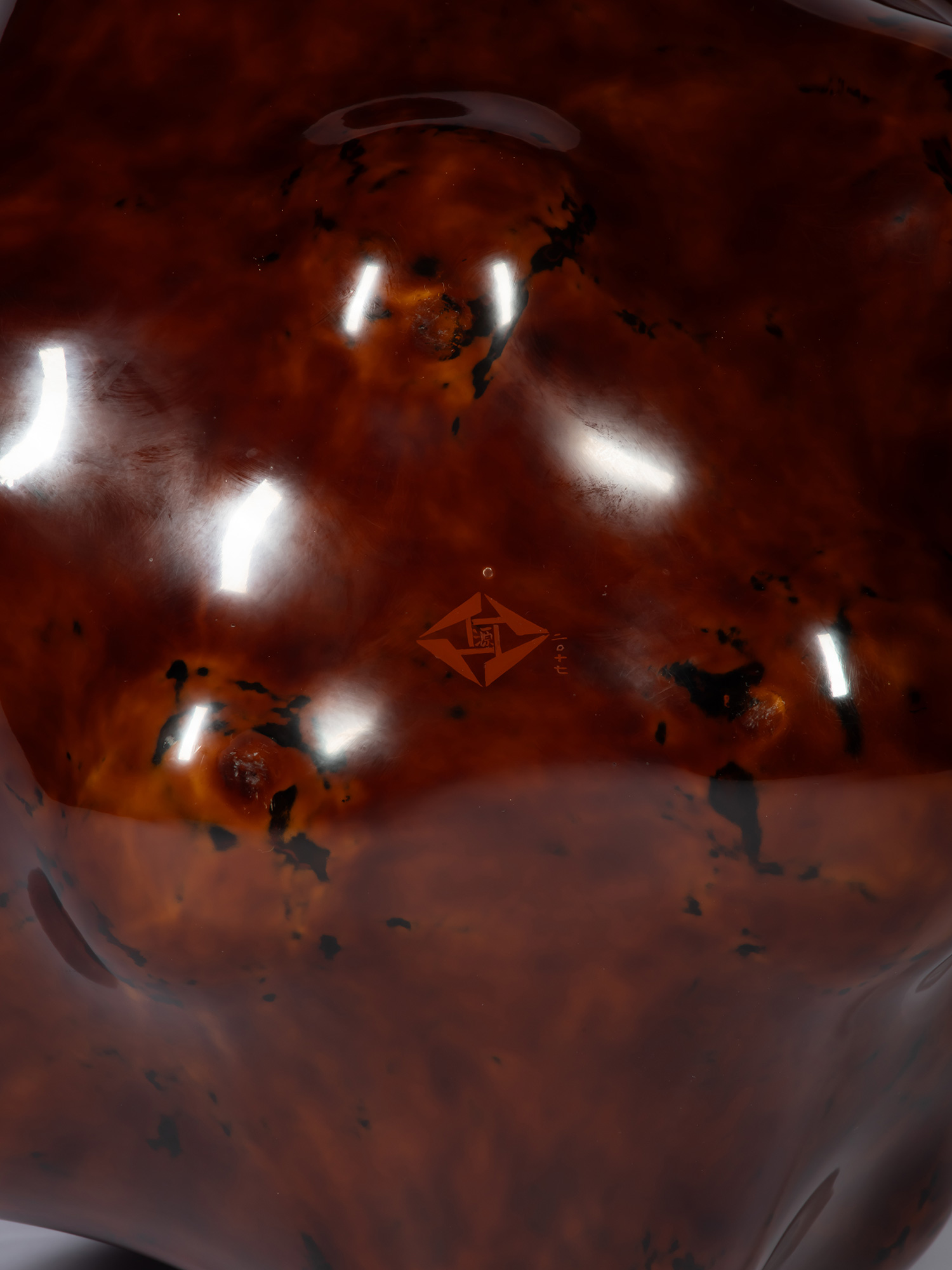 Close-up detail of Surface Tactility #5 showing the artist’s signature etched into the glossy reddish-brown...
