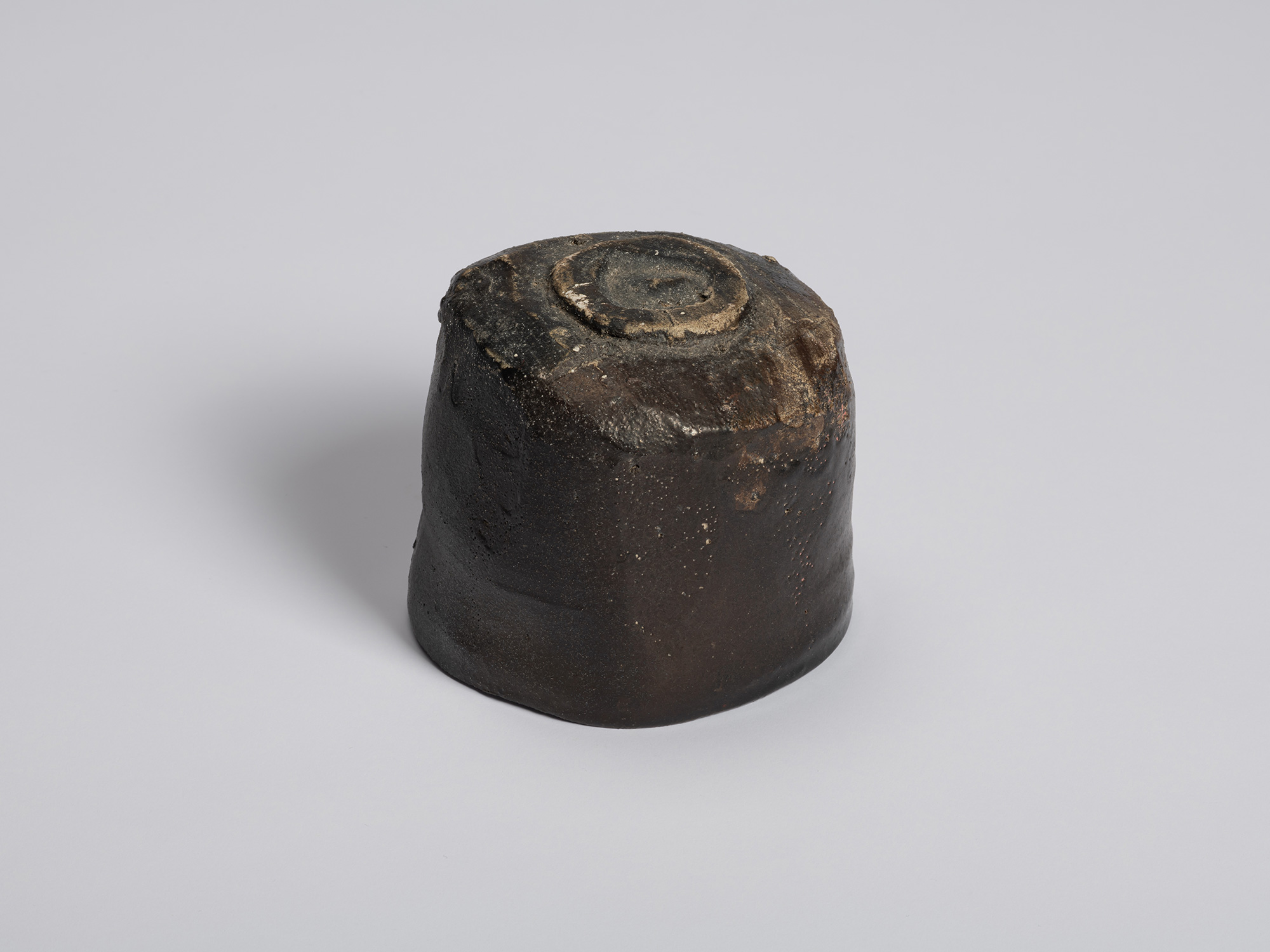 Three-quarter underside view of a hikidashi-type tea bowl by Shiro Tsujimura. The elevated foot...