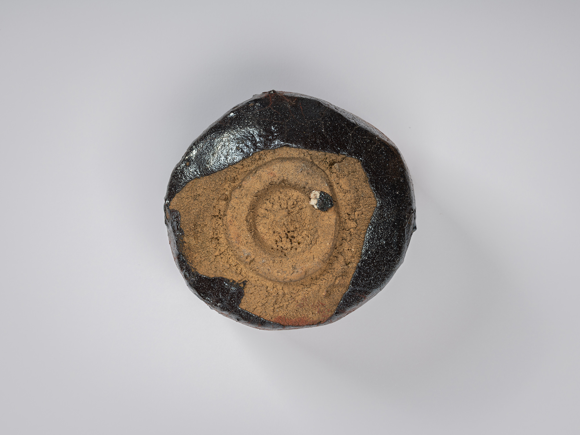 Bottom view of the tea bowl showing the circular foot ring set within a broad area of exposed clay....
