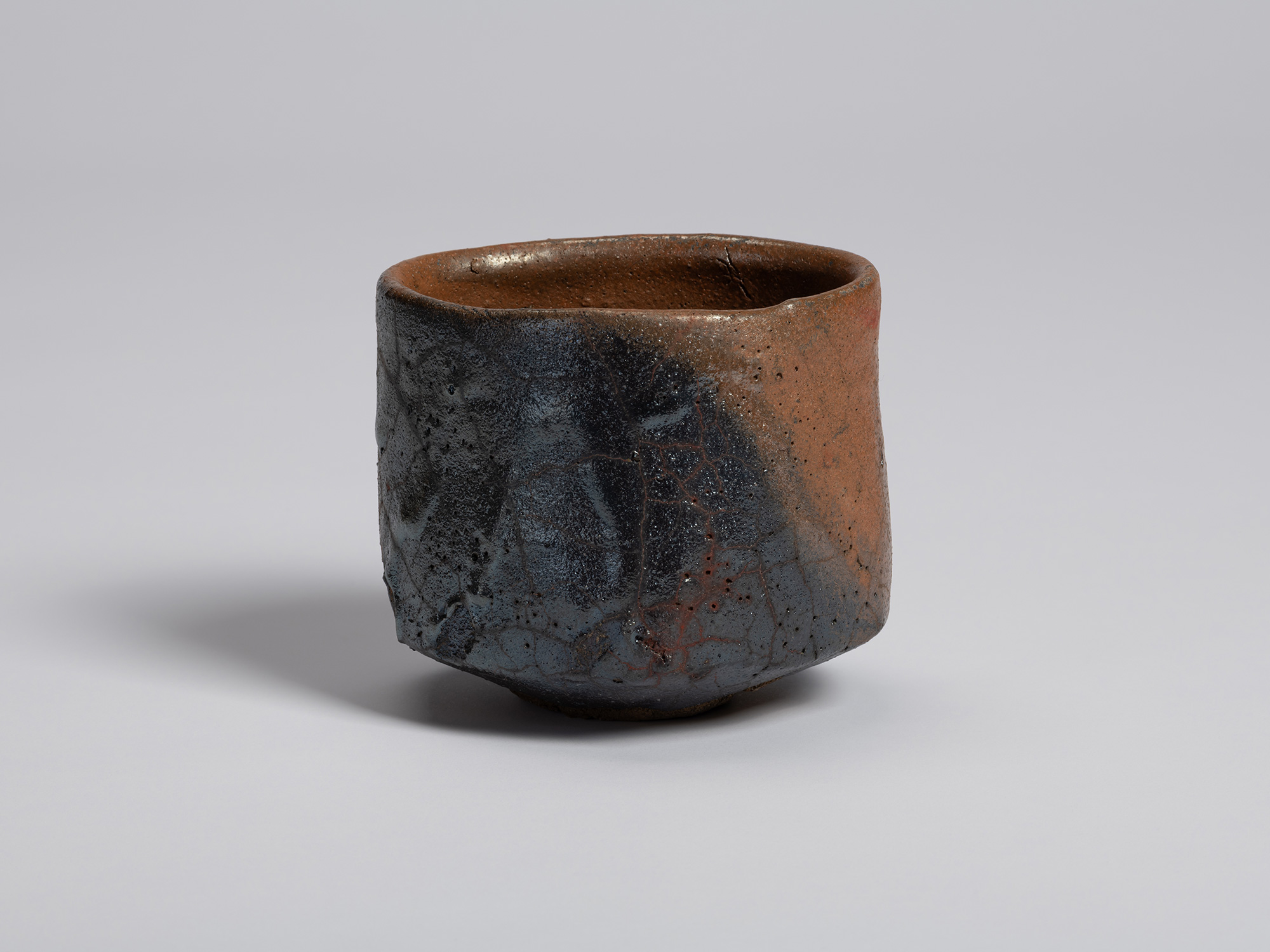 View of a hand-formed tea bowl by Shiro Tsujimura. The cylindrical form features a broad field...