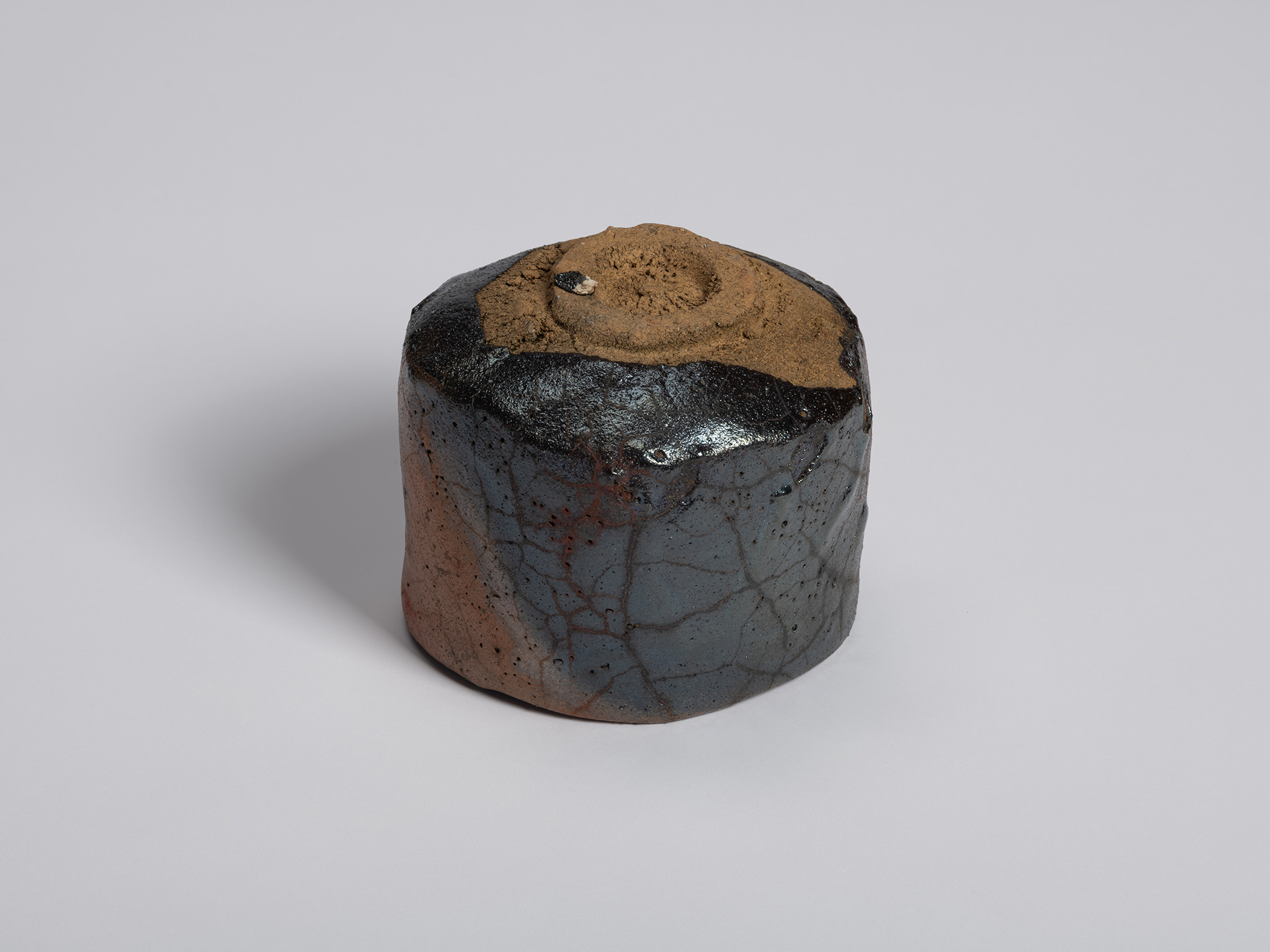 Underside view of the tea bowl revealing a rough, unglazed clay foot ring surrounded by a glossy...