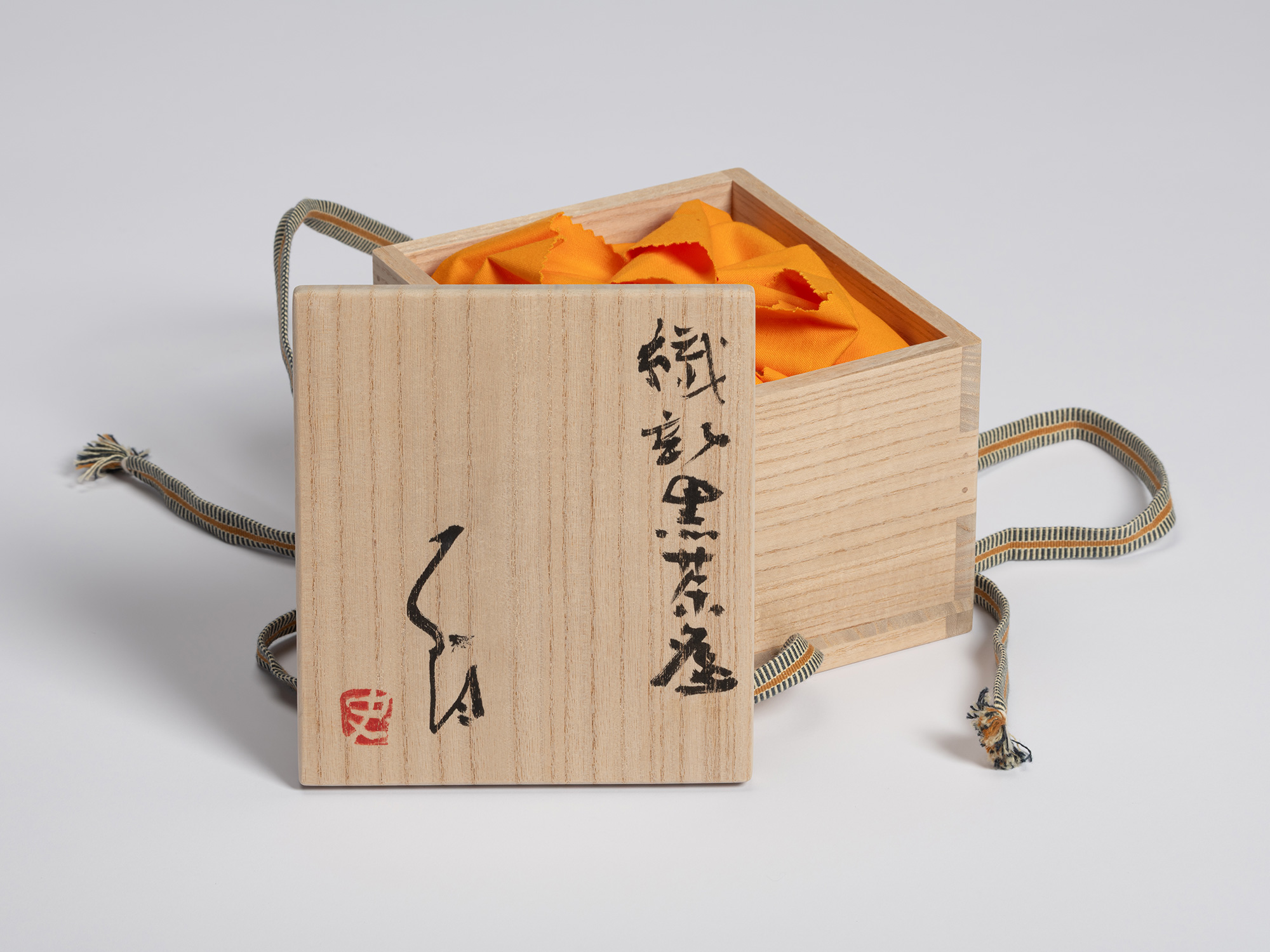 Wooden tomobako for a tea bowl by Shiro Tsujimura shown with the lid leaning against the open box....