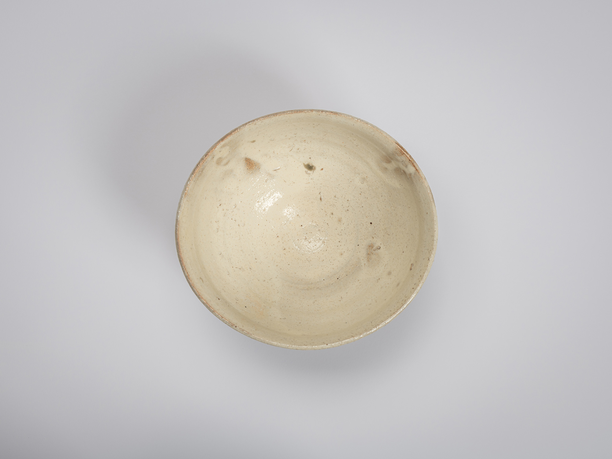 Overhead view looking into Shiro Tsujimura’s tea bowl. The interior is coated in a soft cream-white...