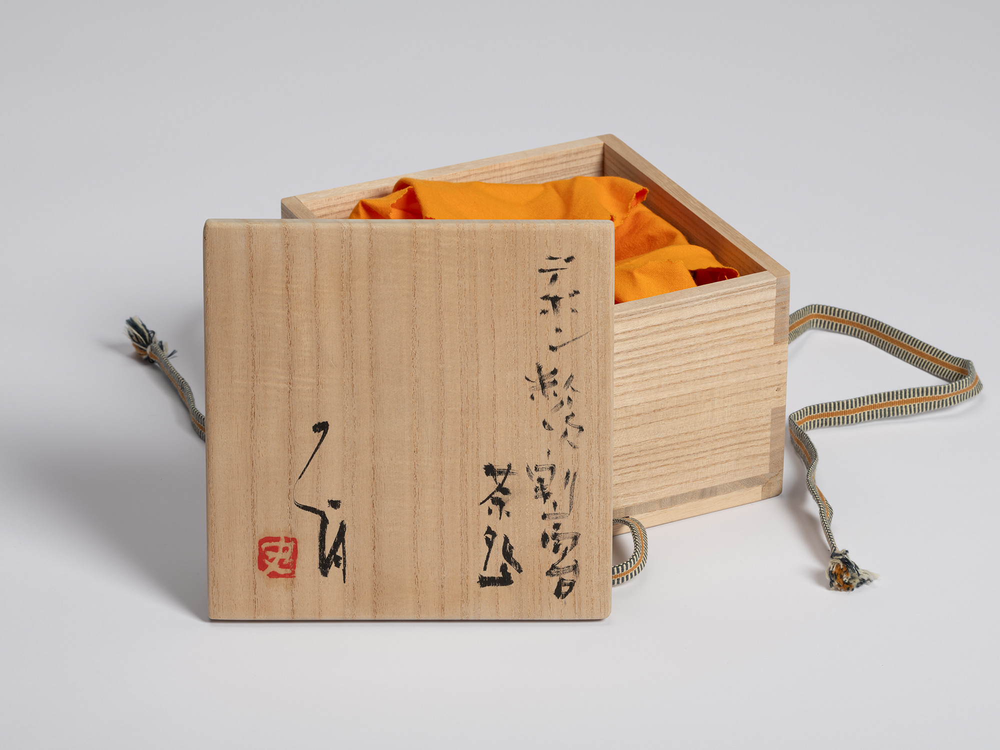 Open kiri wood tomobako for Shiro Tsujimura’s tea bowl with a tripodal foot. The lid is placed...