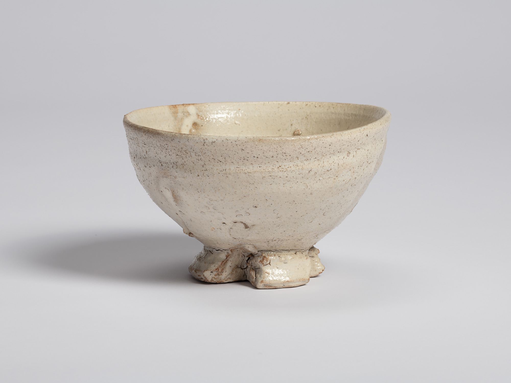 View of a white-glazed tea bowl by Shiro Tsujimura. The rounded body displays subtle shifts in...