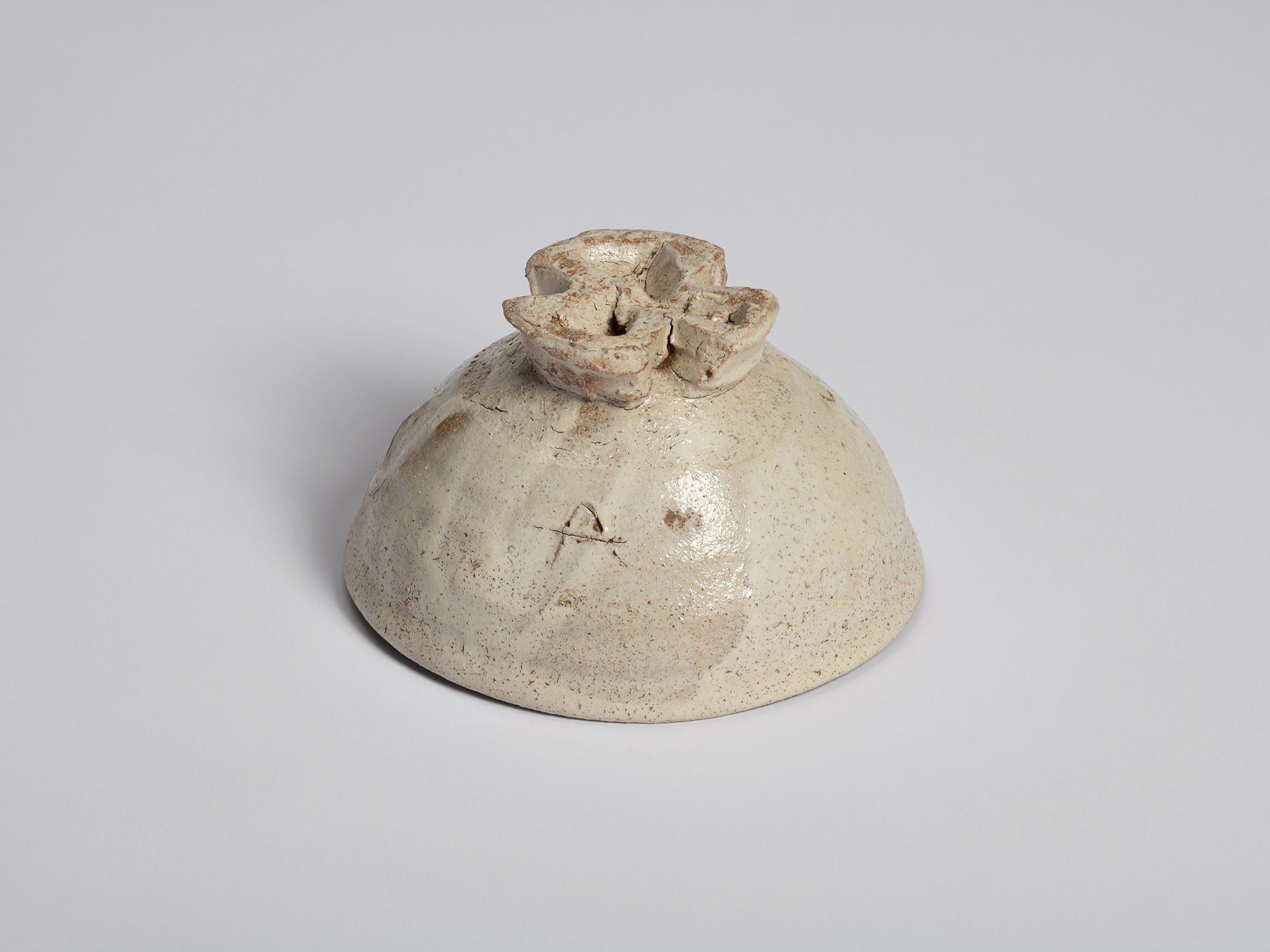 Underside view of the tea bowl turned upside down, revealing the sculptural tripodal foot. The...