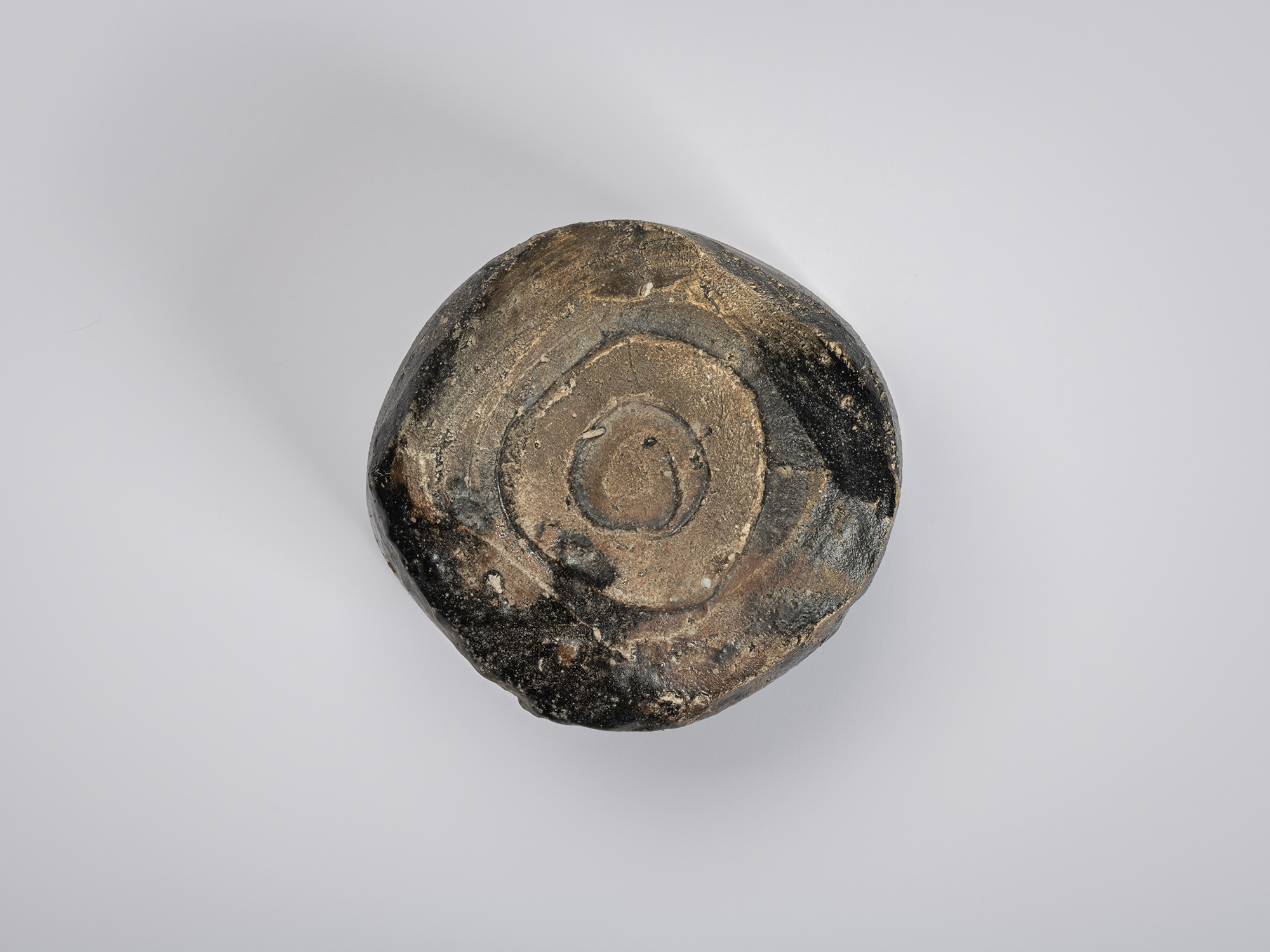 Bottom view of a Hikidashi-style tea bowl by Shiro Tsujimura. The foot is carved into a faceted,...