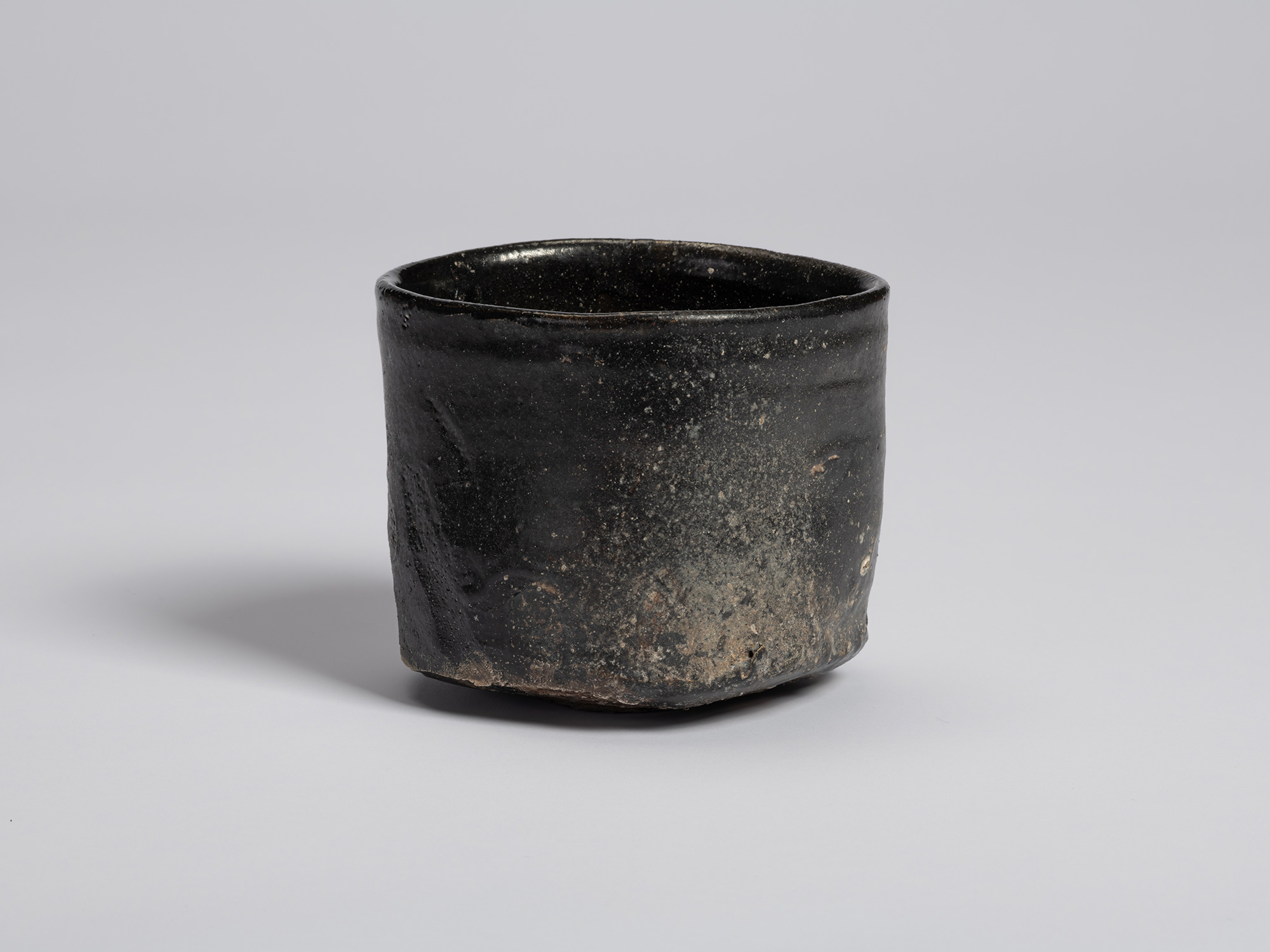 View of a Hikidashi-style tea bowl by Tsujimura. A broad area of pale gray ash accumulation contrasts...
