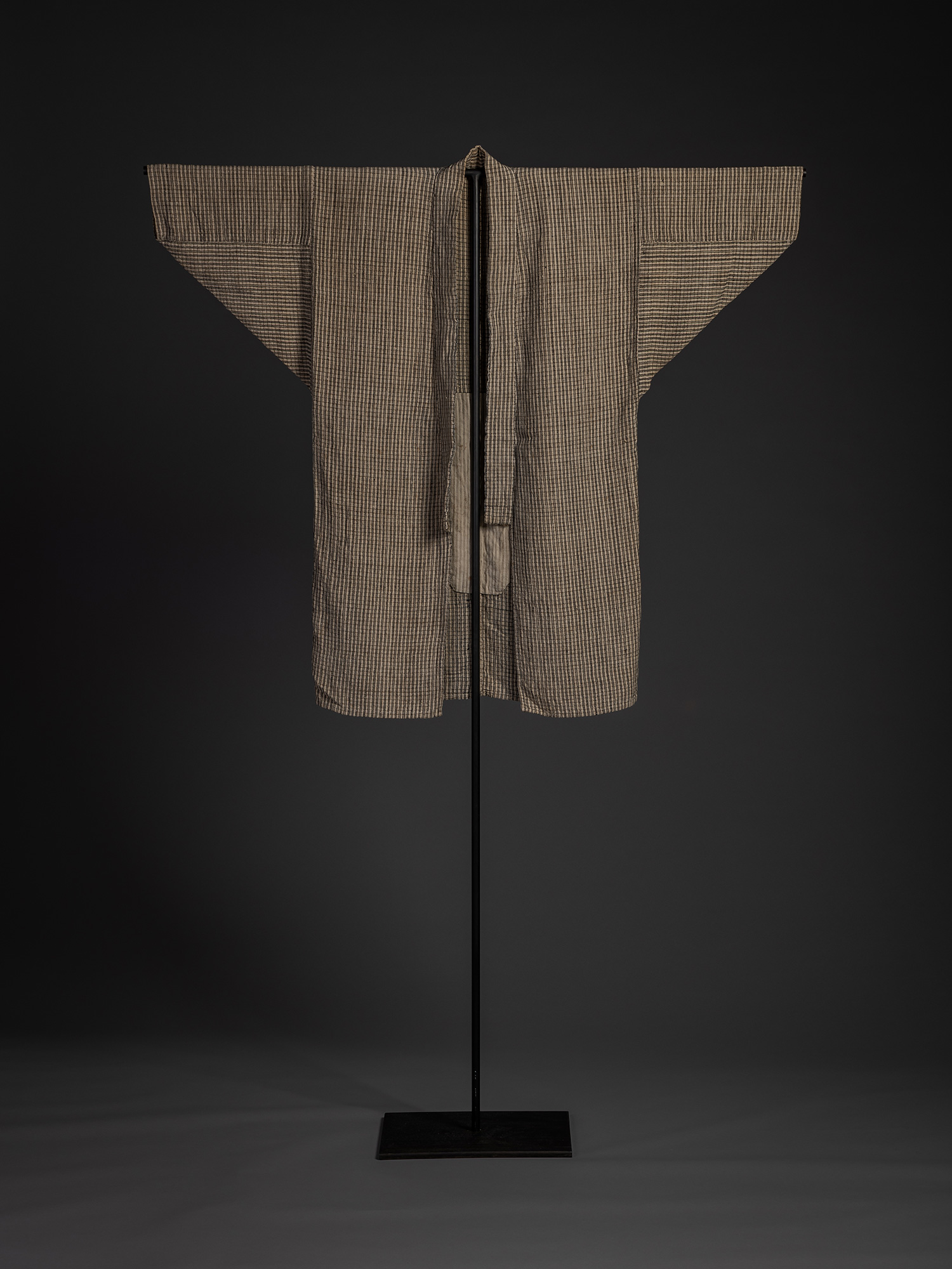 Front view of the Tsushima jacket displayed open on a black stand. The finely woven black-and-natural...