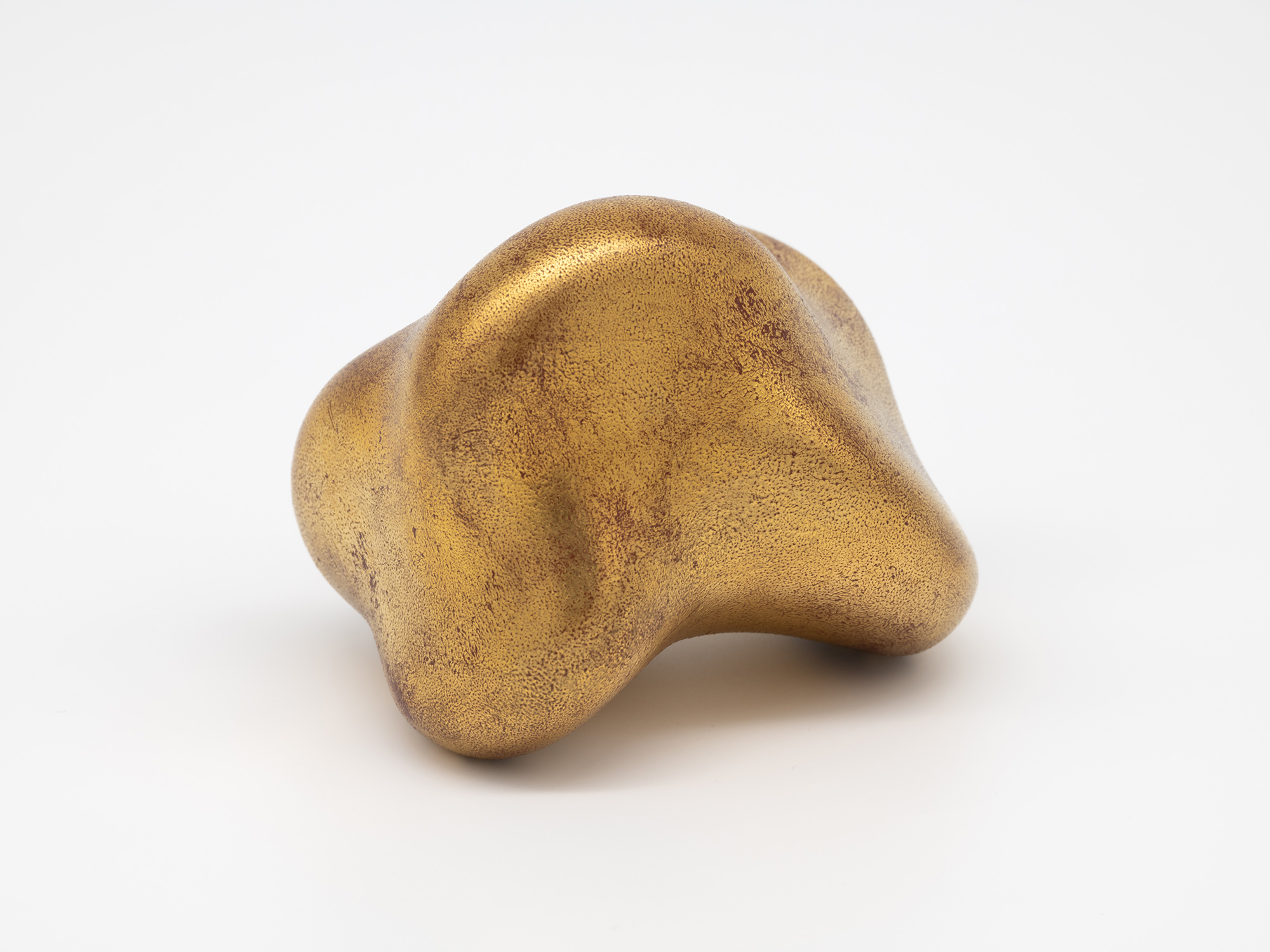 View of Untitled (Faded Gold) showing the sculpture resting on two rounded points. An arched recess...