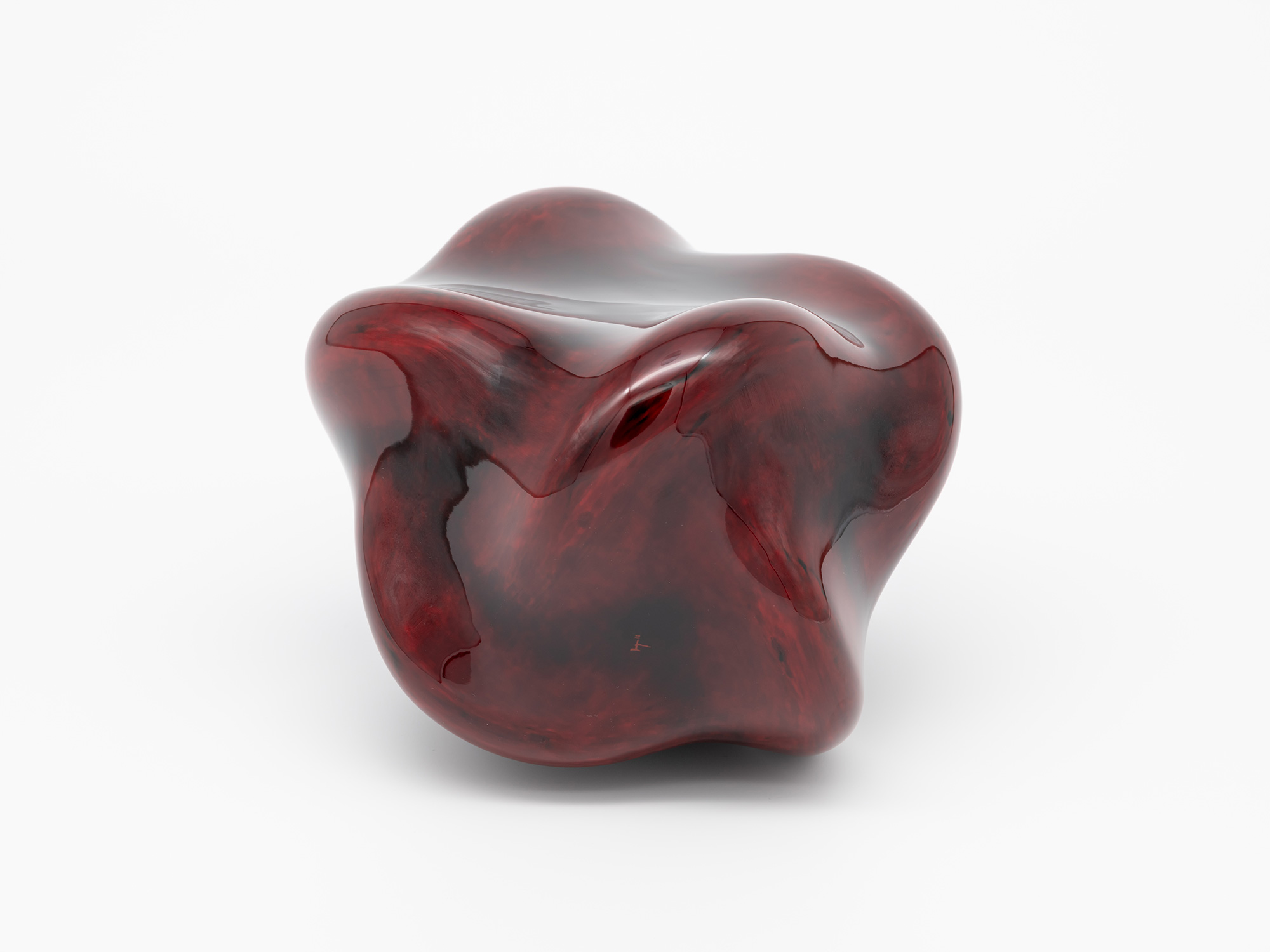 Bottom view of Untitled (Star) showing a broad, gently curved underside with a polished red lacquer...