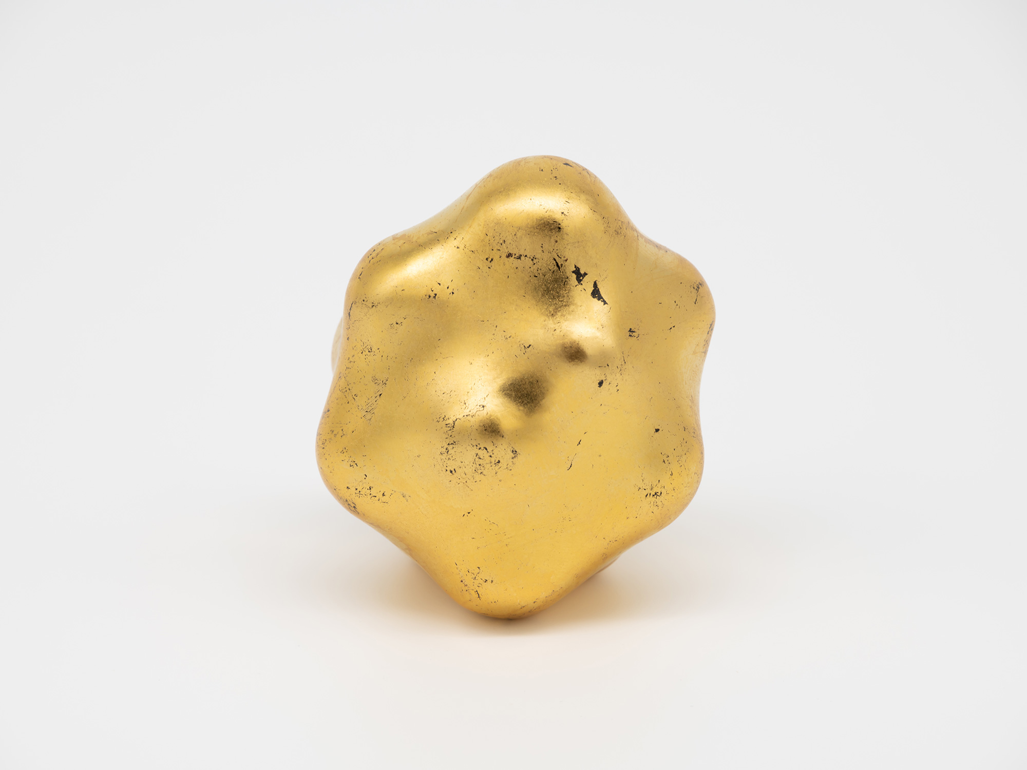 Front view of Untitled by Genta Ishizuka. The gold leaf-covered sculpture presents an irregular...
