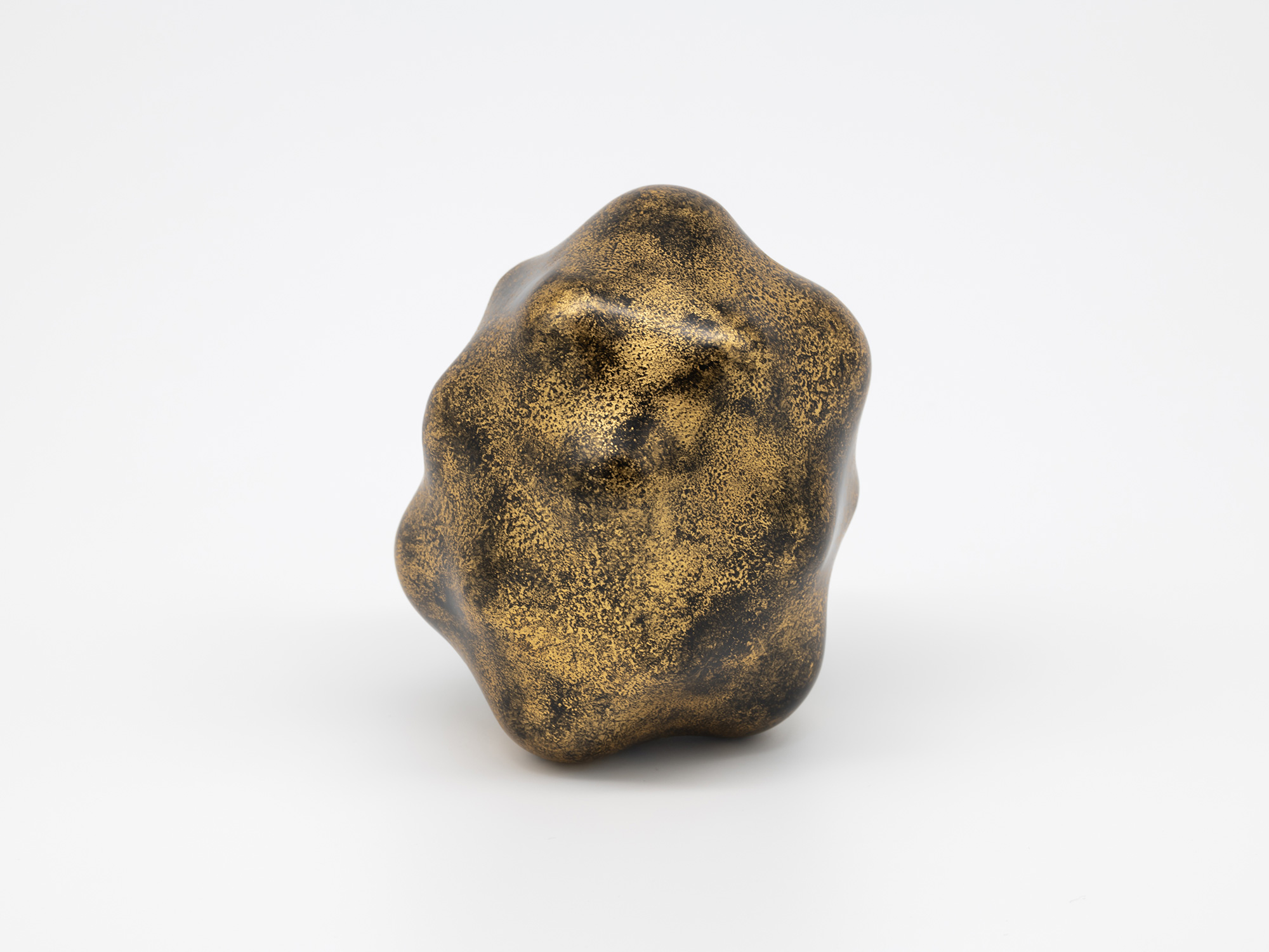 Side view of the sculpture revealing a series of softly rounded lobes that merge into a compact,...