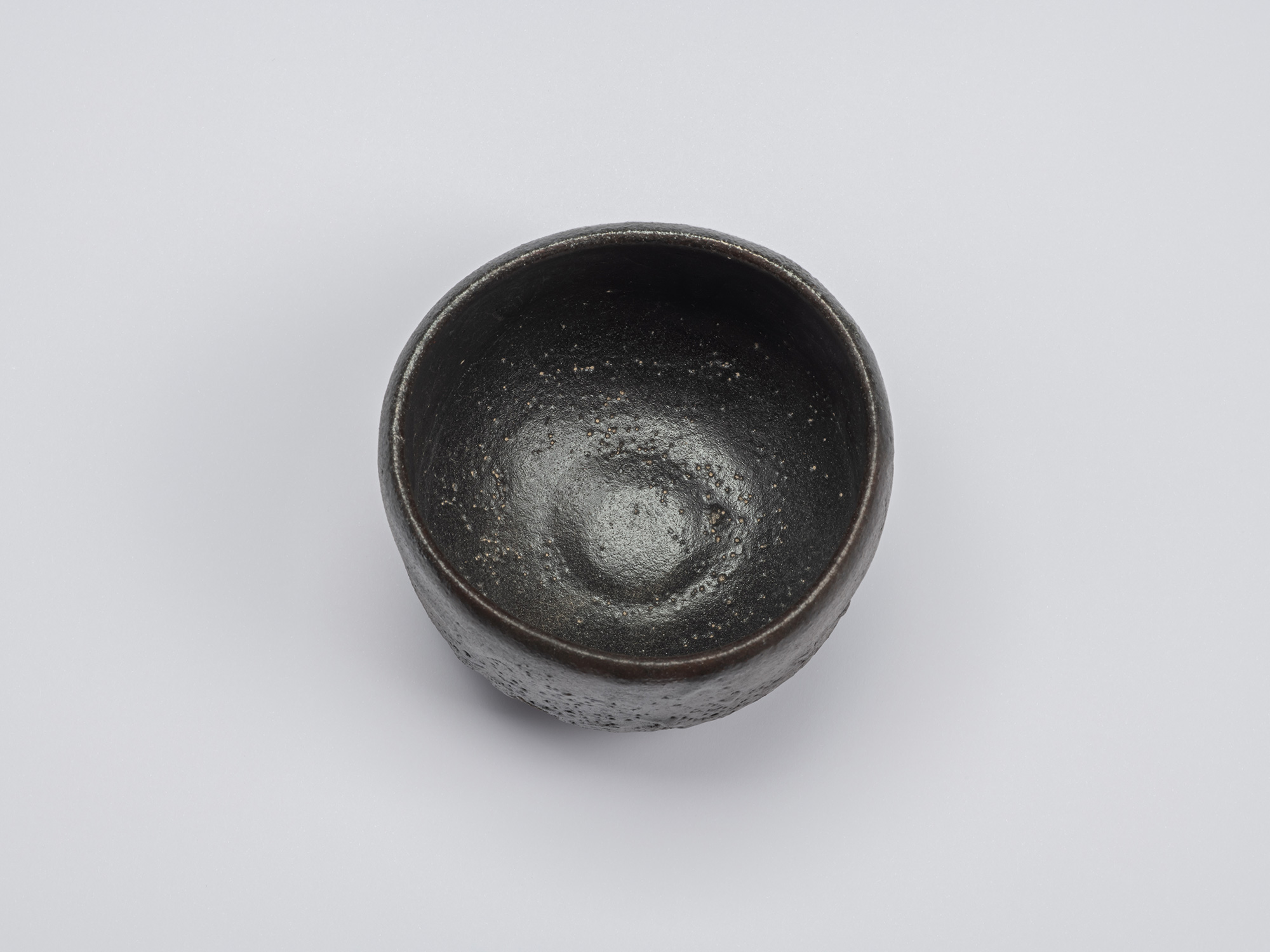 Overhead view of Chawan No. 11 by Shiro Tsujimura showing a glossy charcoal-black interior with...