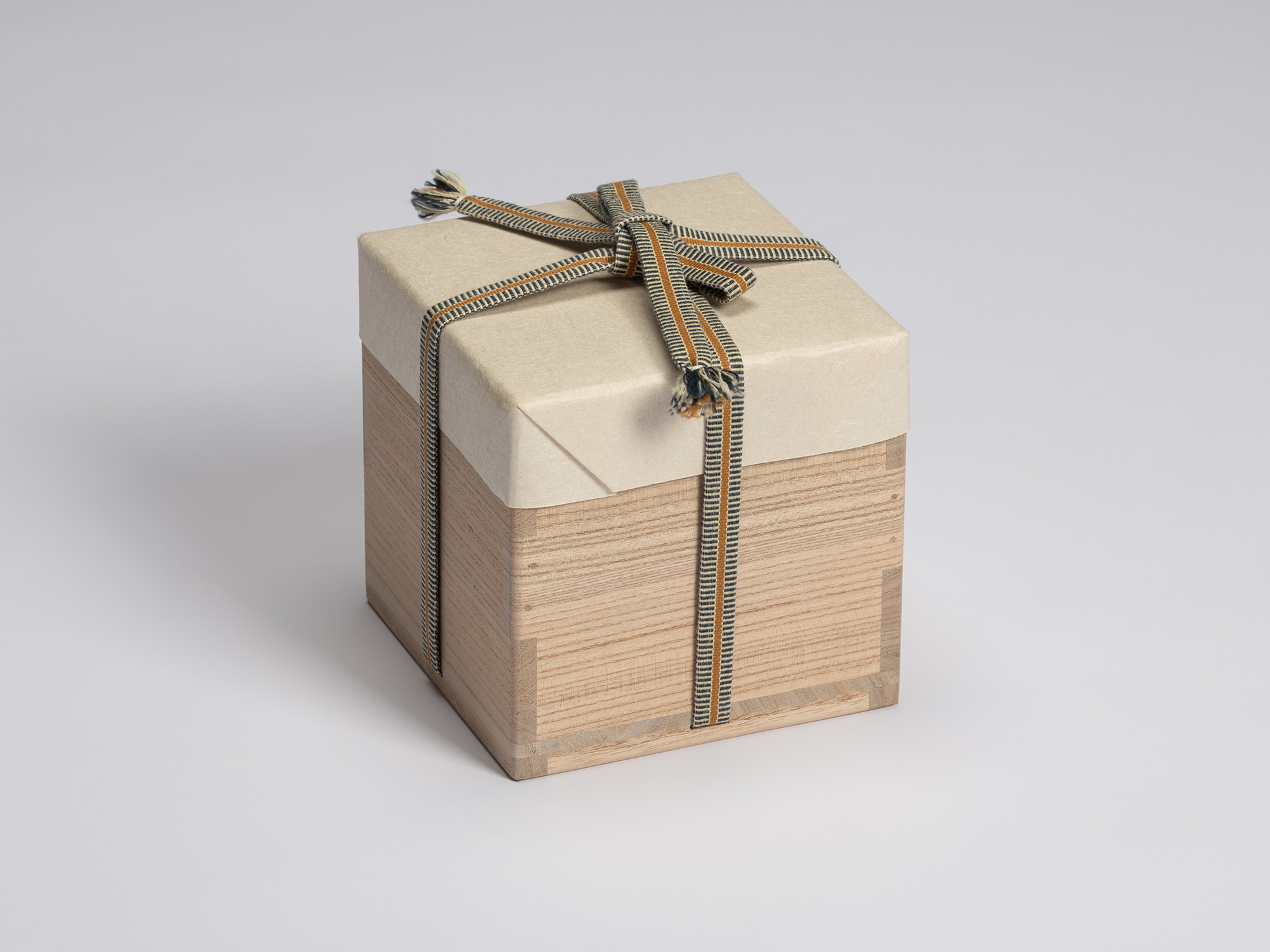 Wooden tomobako for Chawan No. 11 wrapped in protective paper and secured with a blue, tan, and...